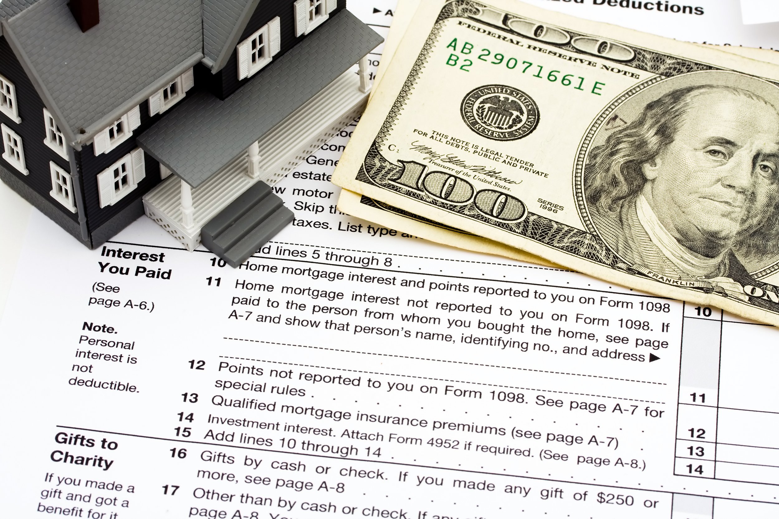 Model house sitting on tax papers with money