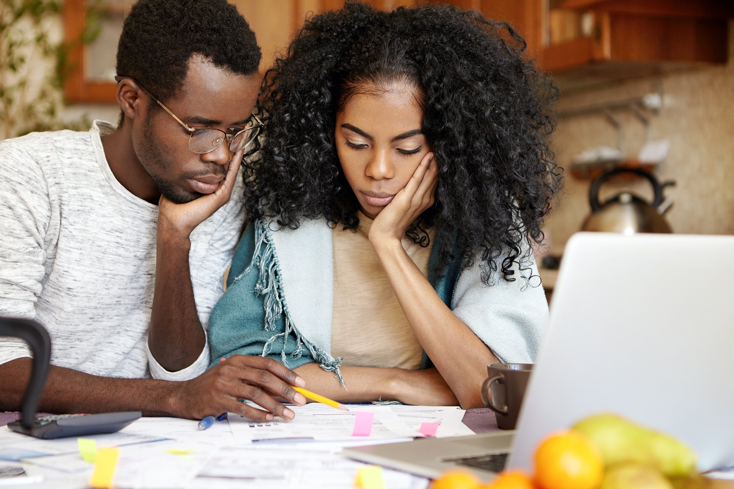 Unhappy couple sitting at home doing bills or looking at finances