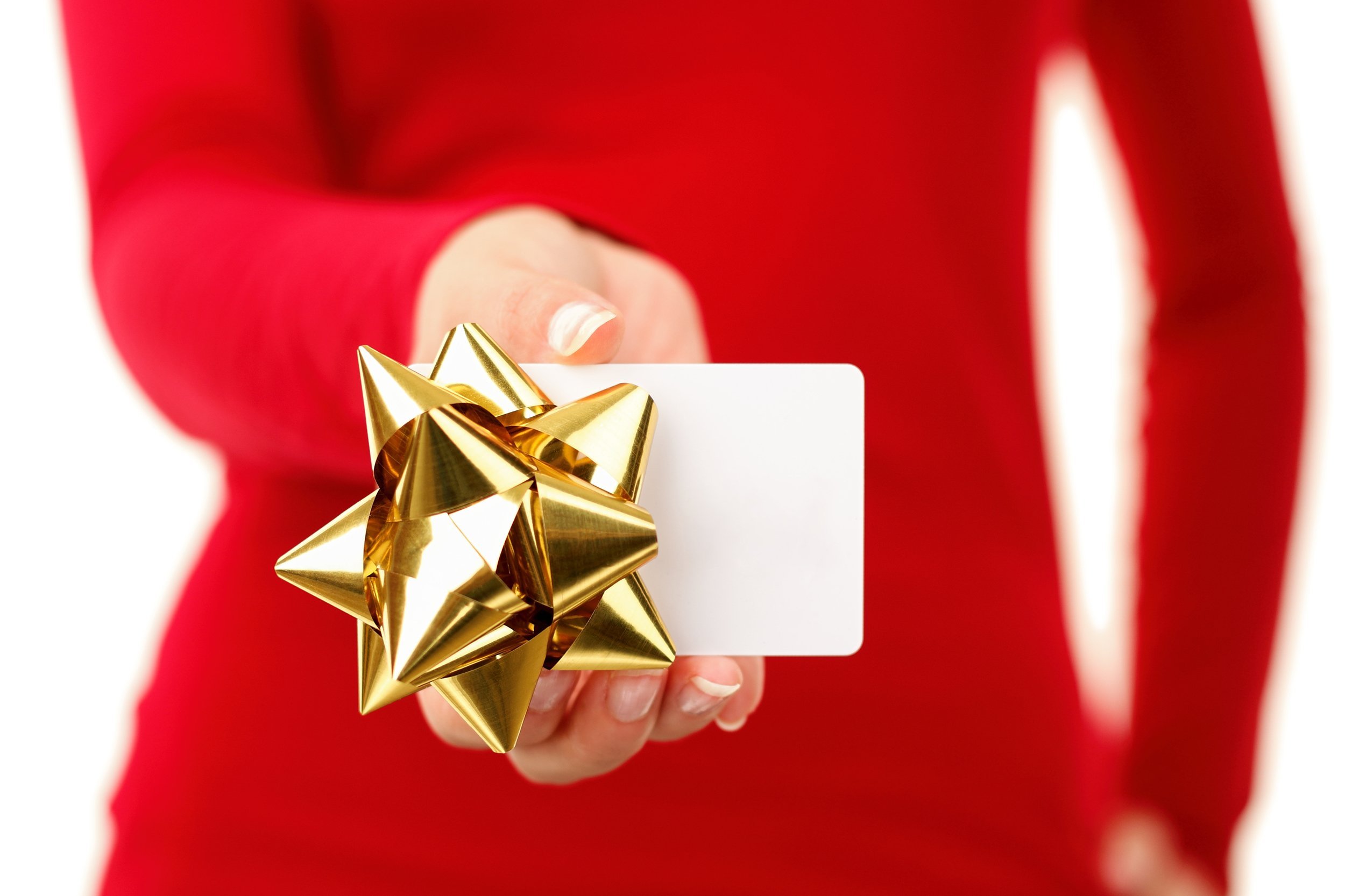 Closeup of woman in a red shirt giving a white gift card with a gold bow