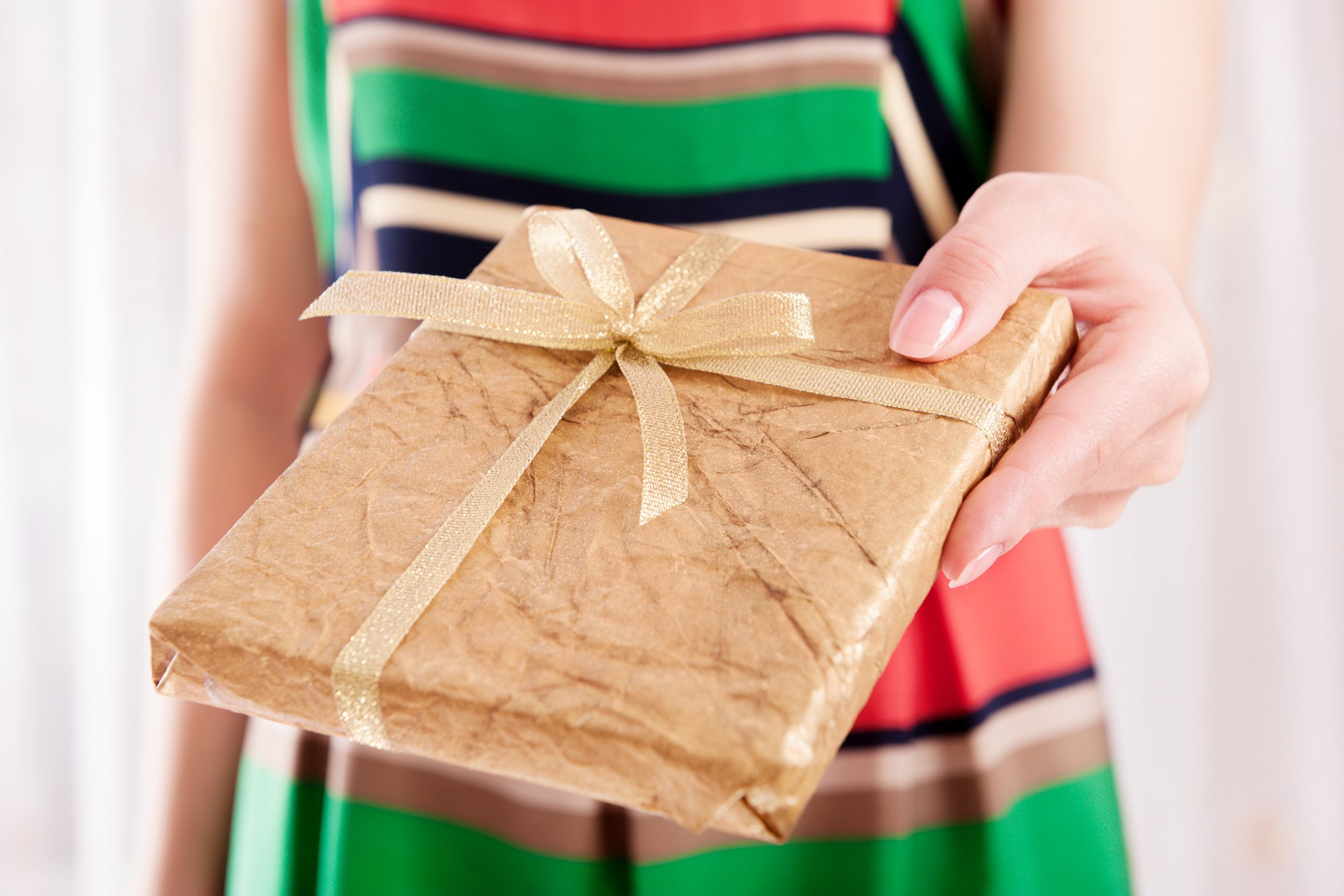 Closeup of woman giving a book or DVD wrapped in rustic brown paper