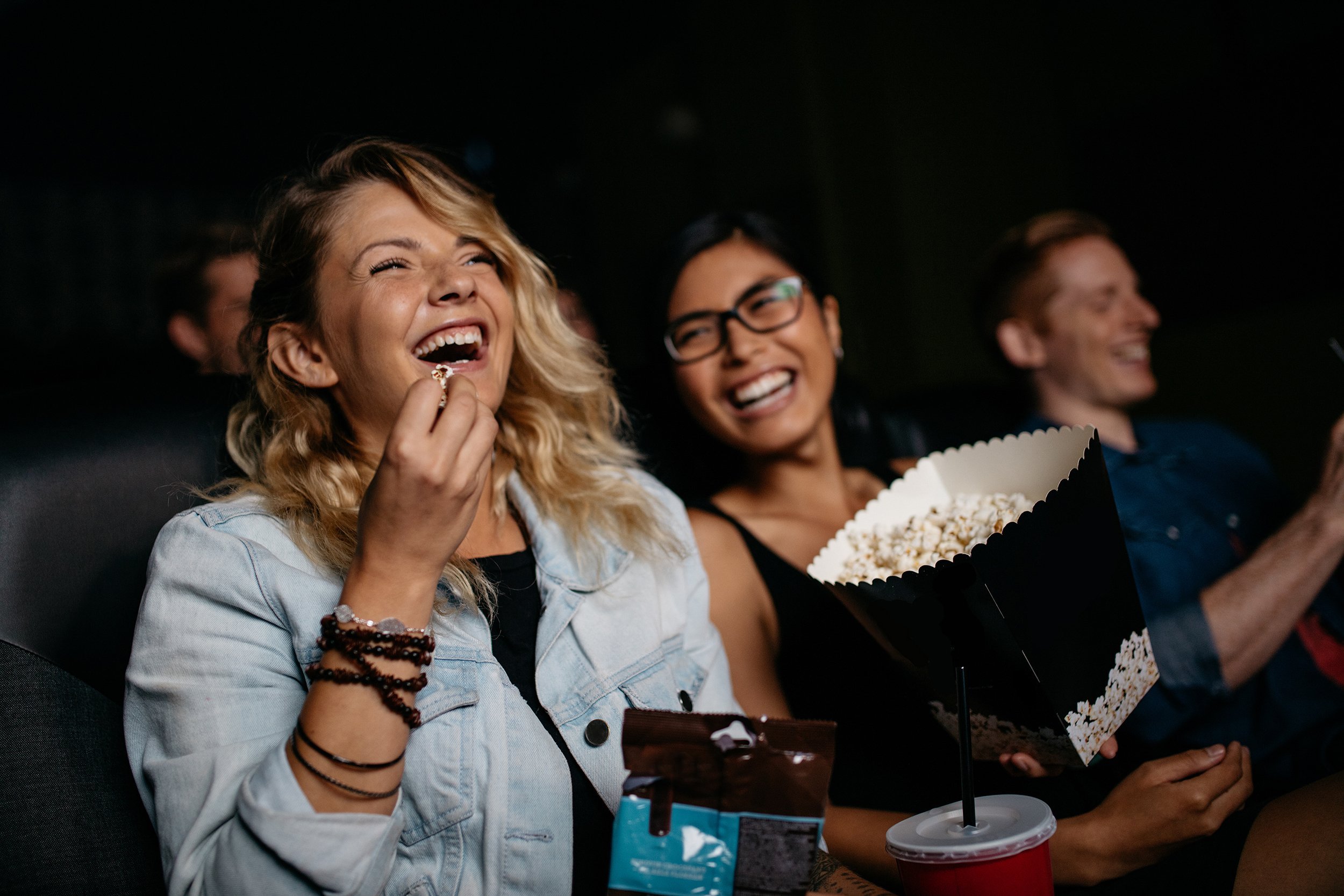 young woman with friends watching movie in theater