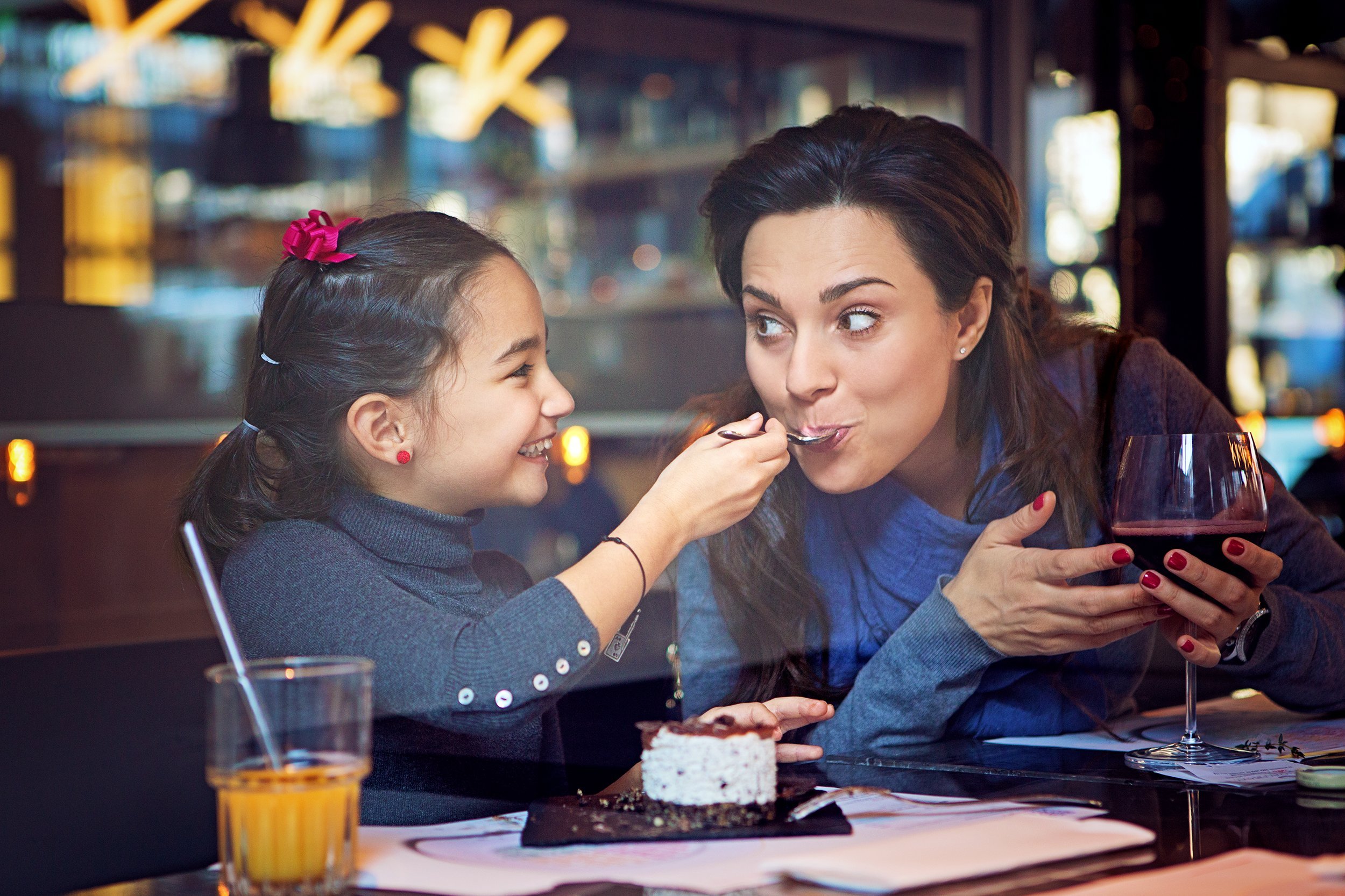 daughter is feeding her mother with cake