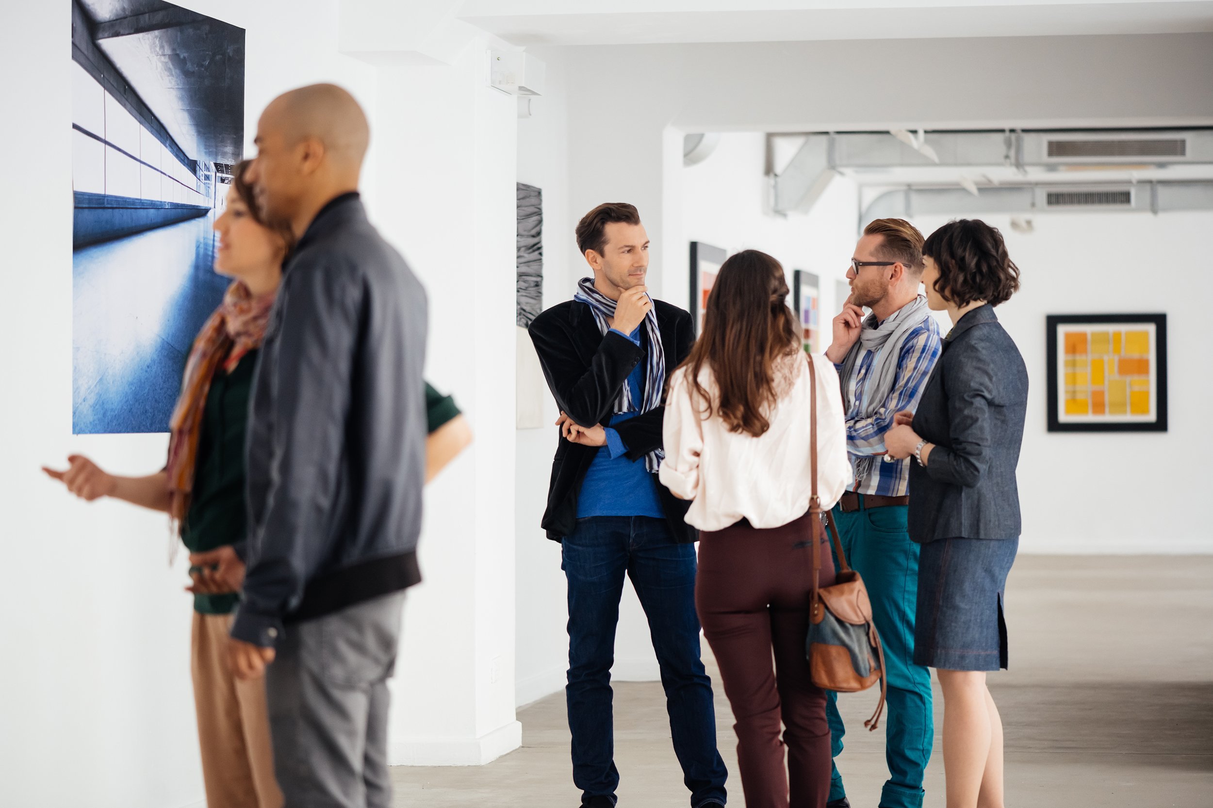 visitors in art gallery looking at artwork and talking