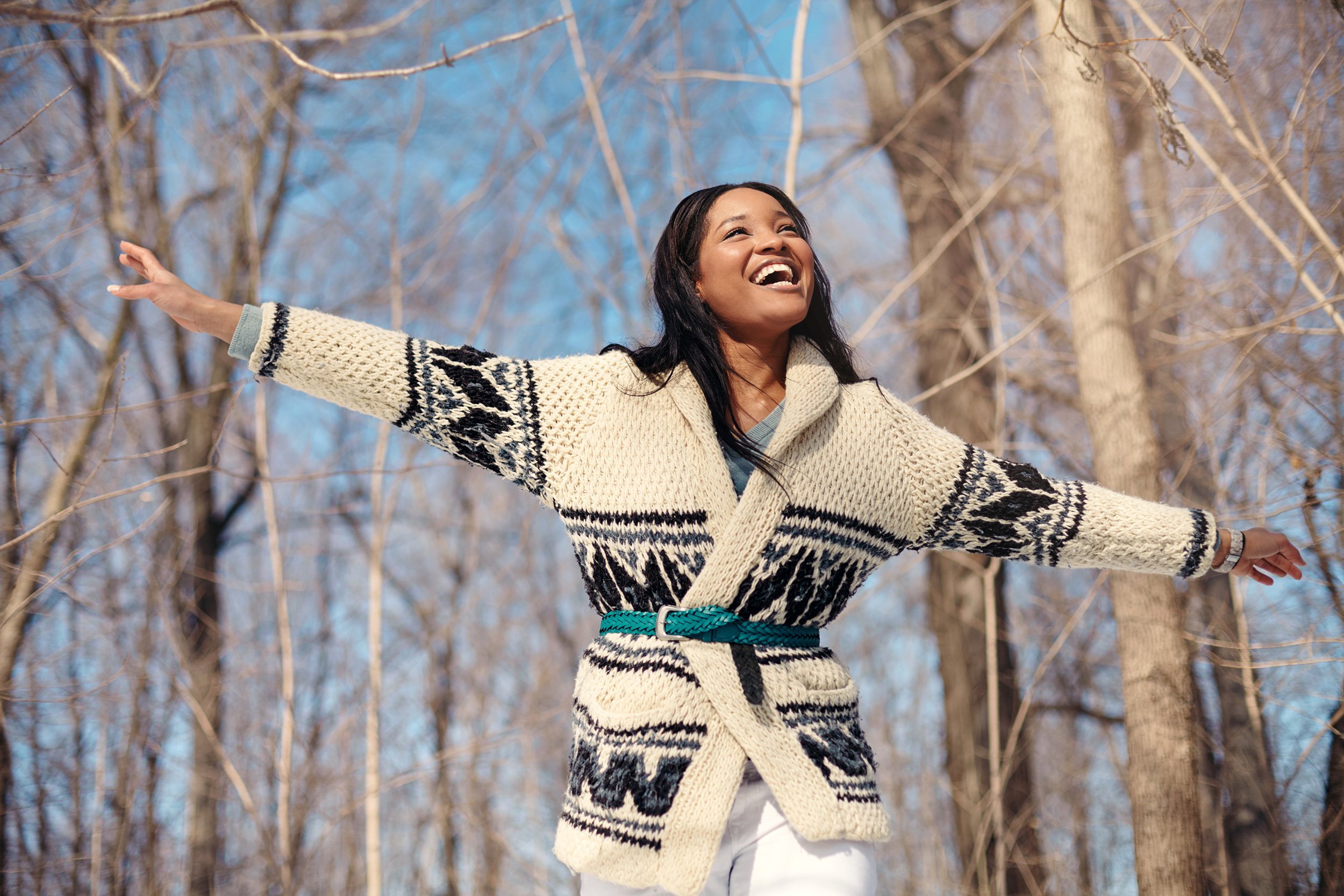 Happy young woman outside in the winter with hands up and smiling