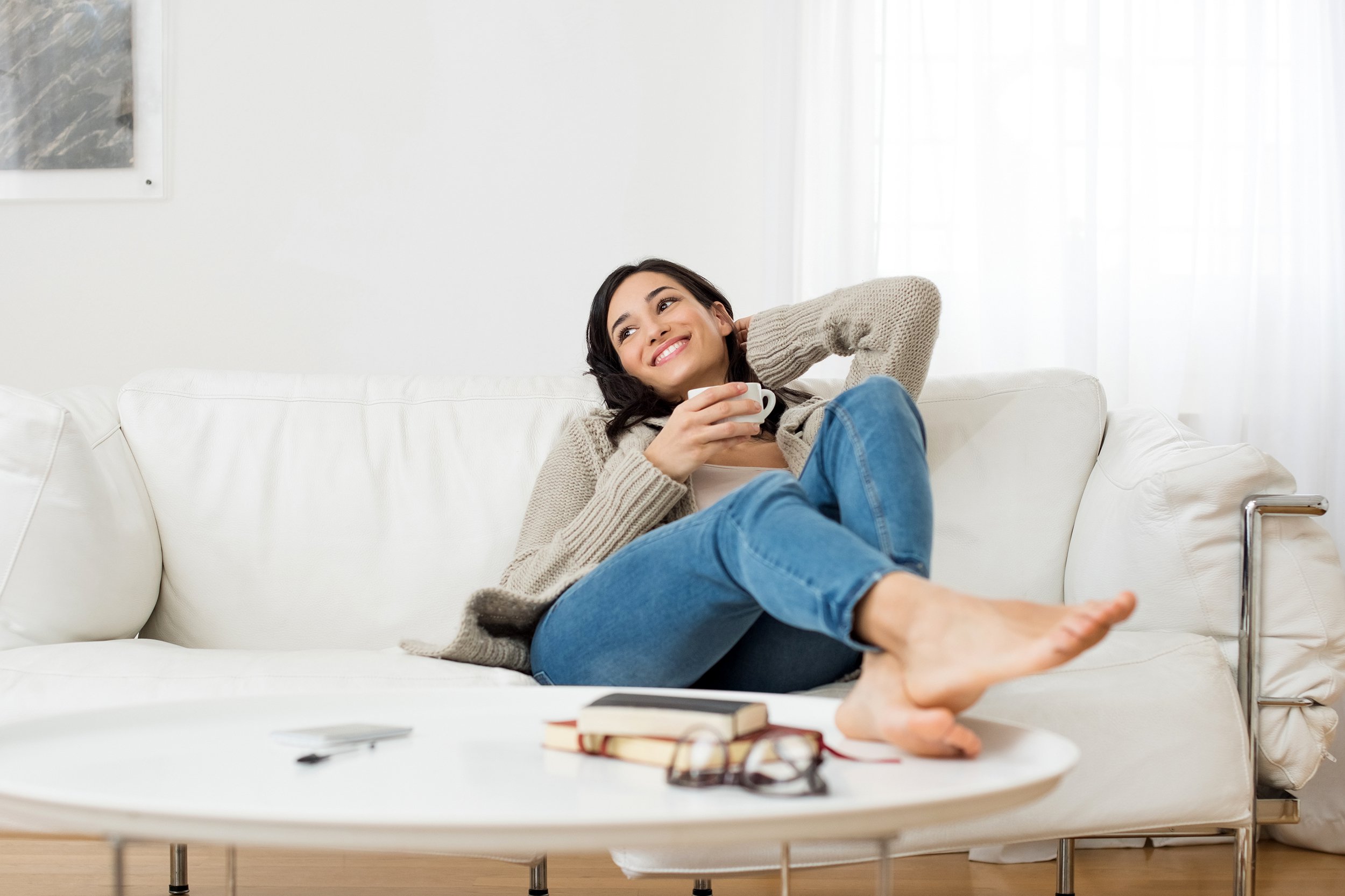 Woman relaxing at home on couch with a cup of coffee or tea
