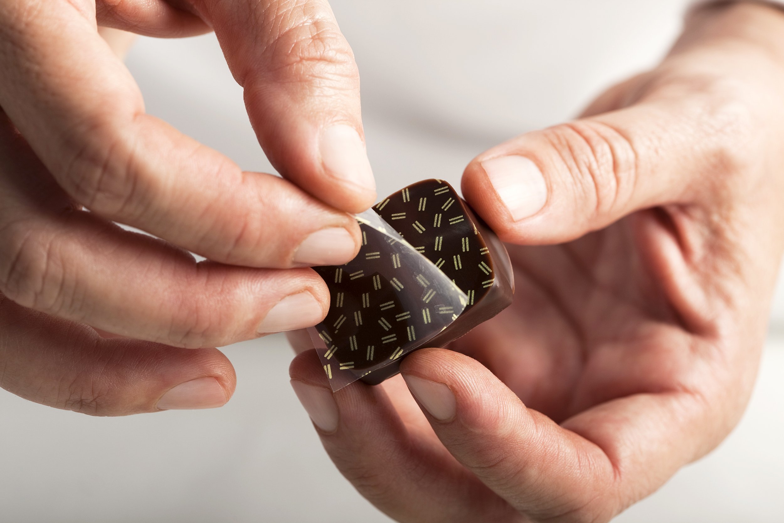 chocolatier hands holding a piece of chocolate