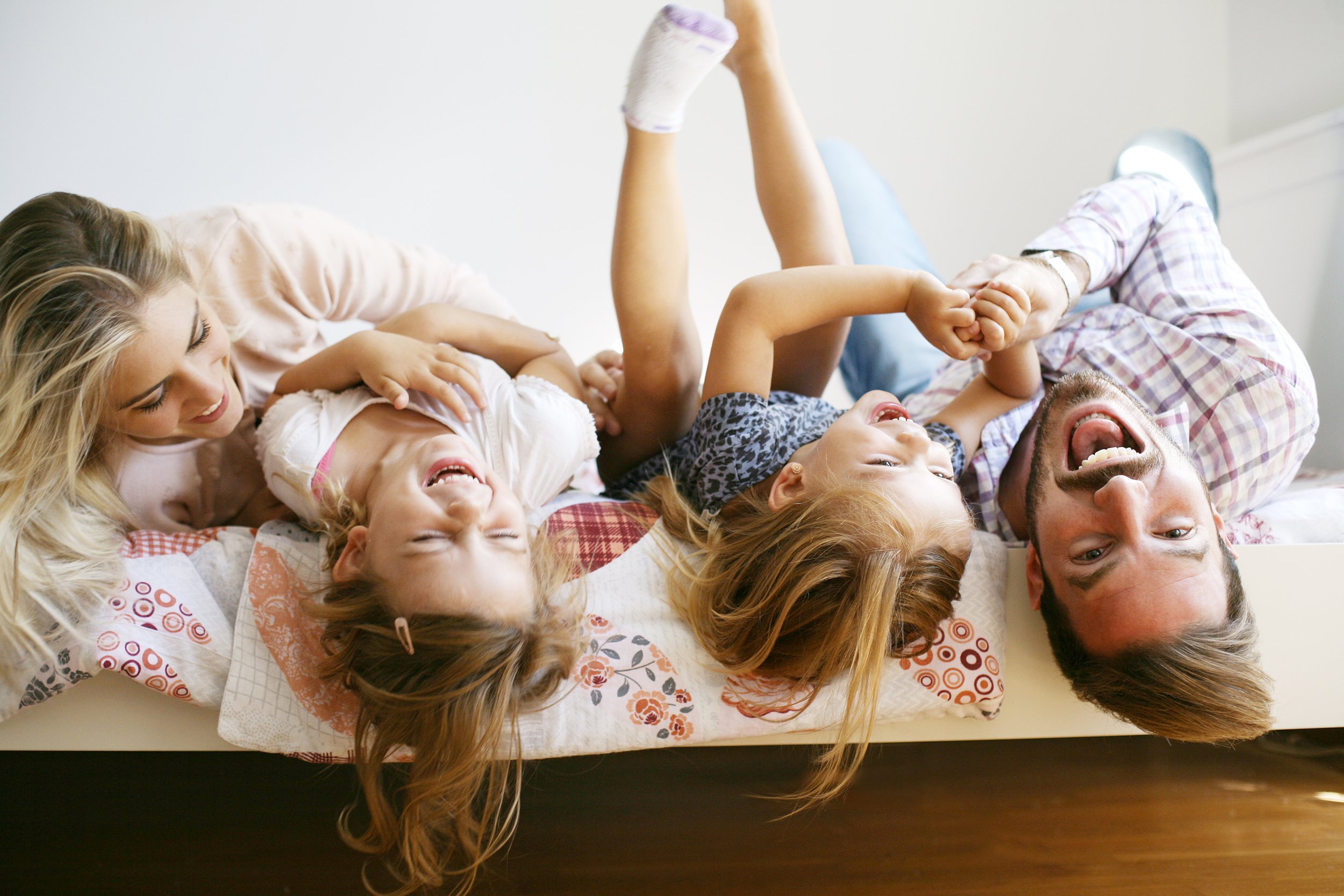Family having fun and playing on the bed with their kids