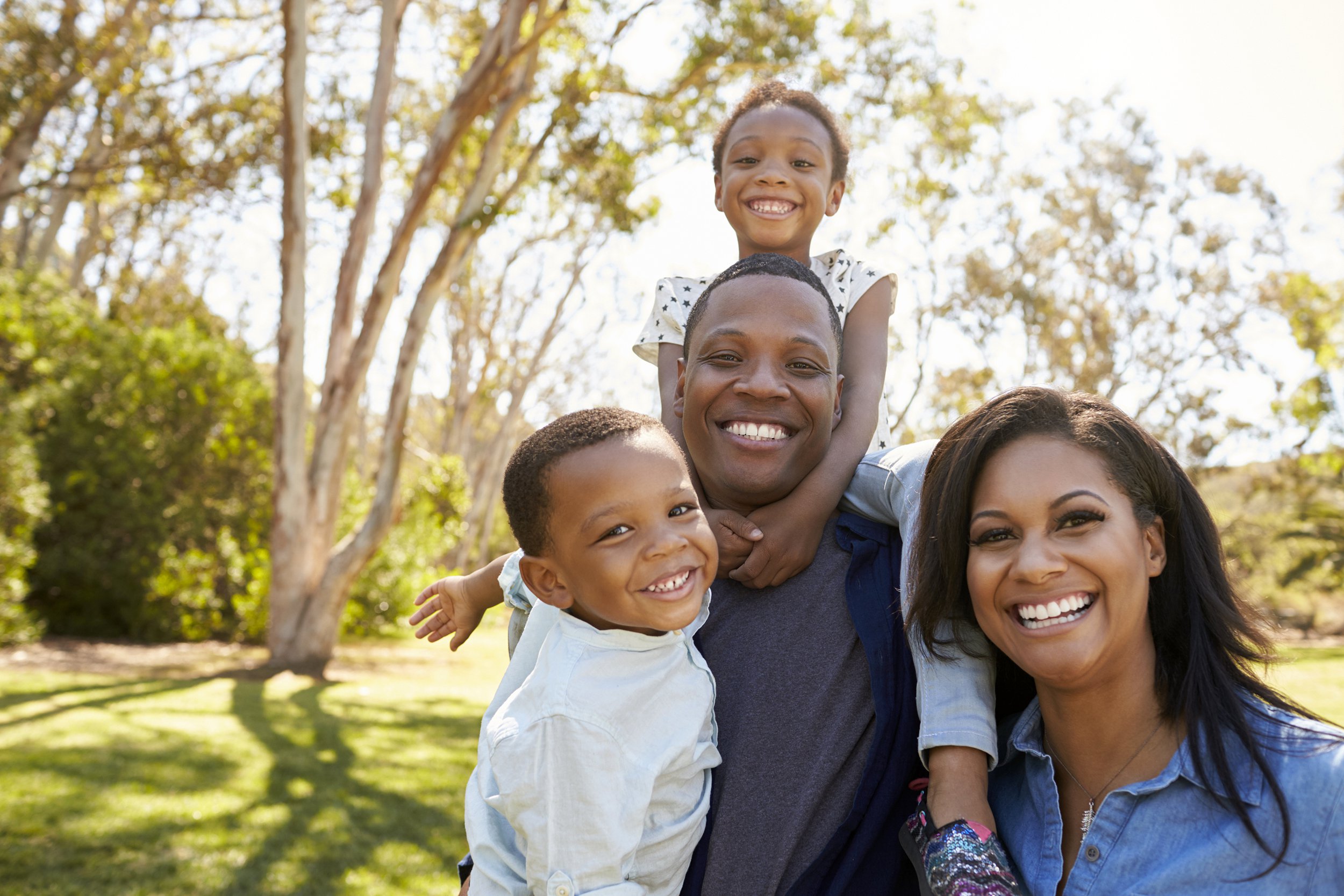Family outside posing for a photo with trees in the background