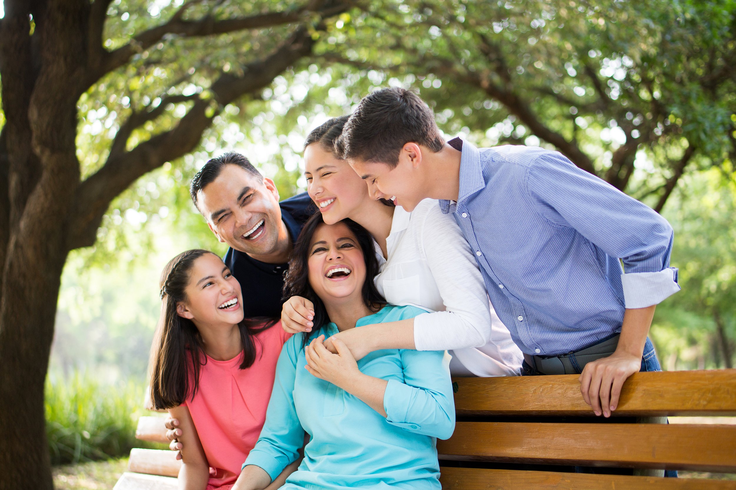 Family on a bench outside laughing and having fun during photo shoot