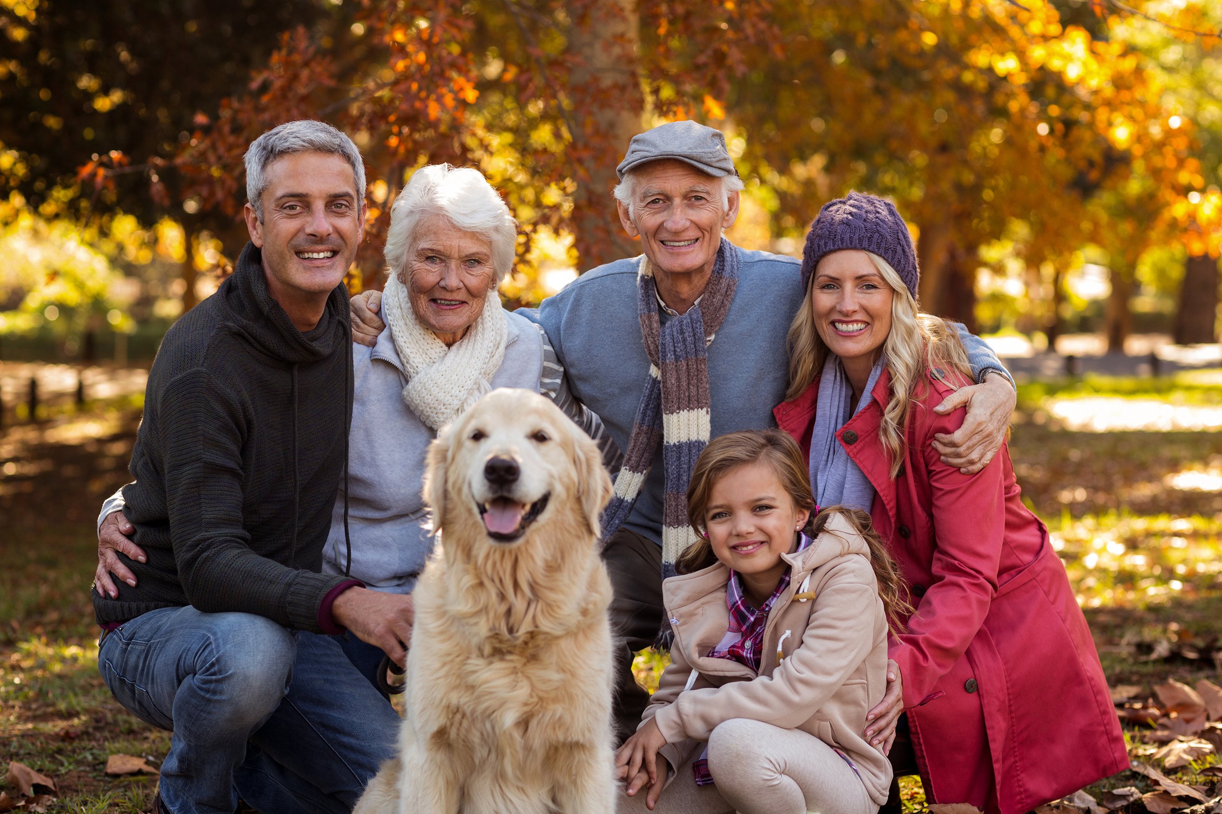Family outside in the fall taking a portrait with their dog