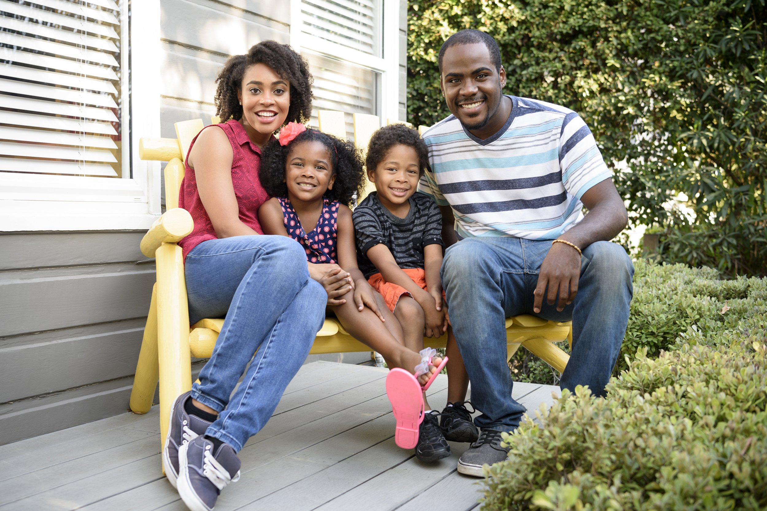 Family sitting on a bench on their front porch taking a photo