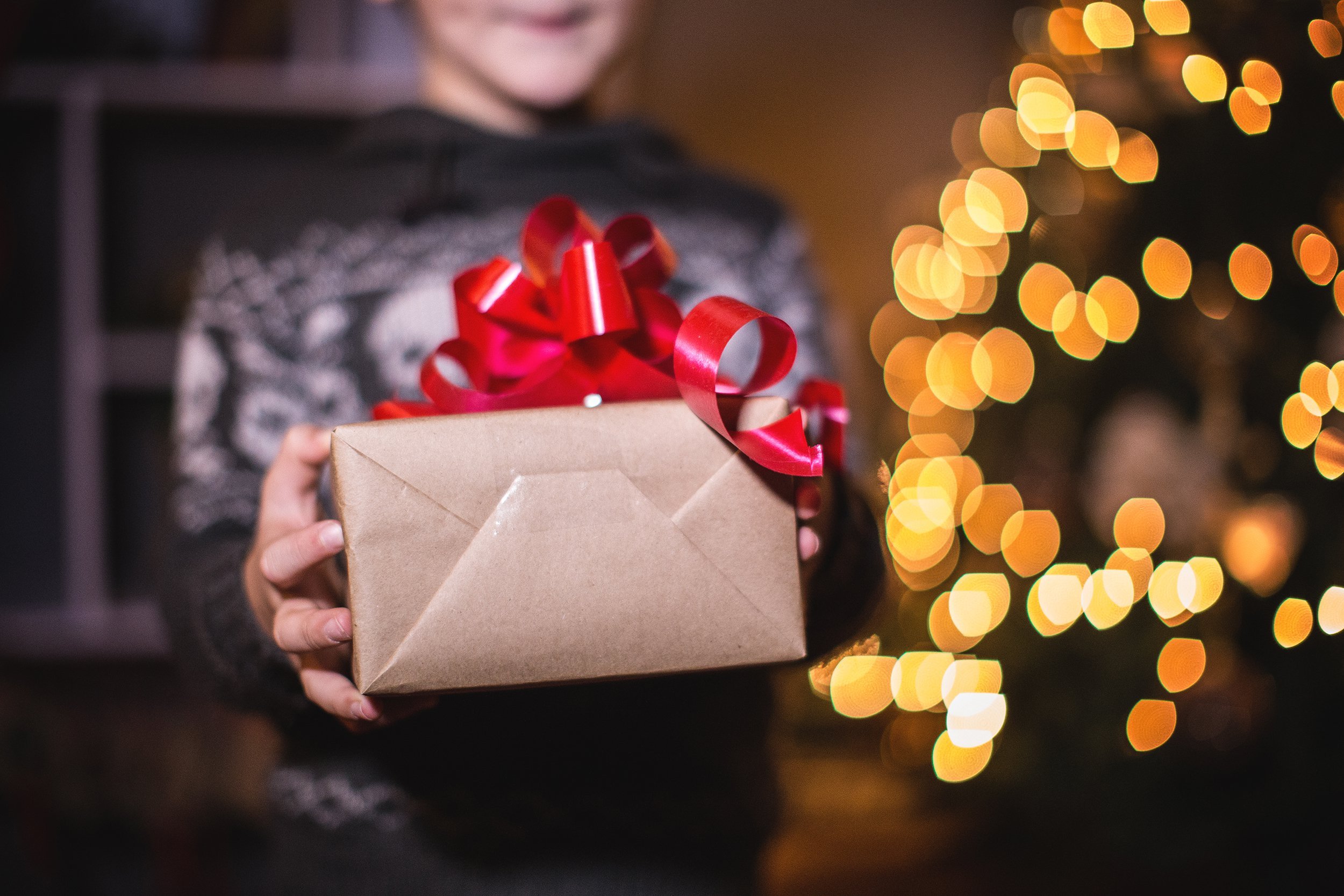 boy holding Christmas gift with tree in background