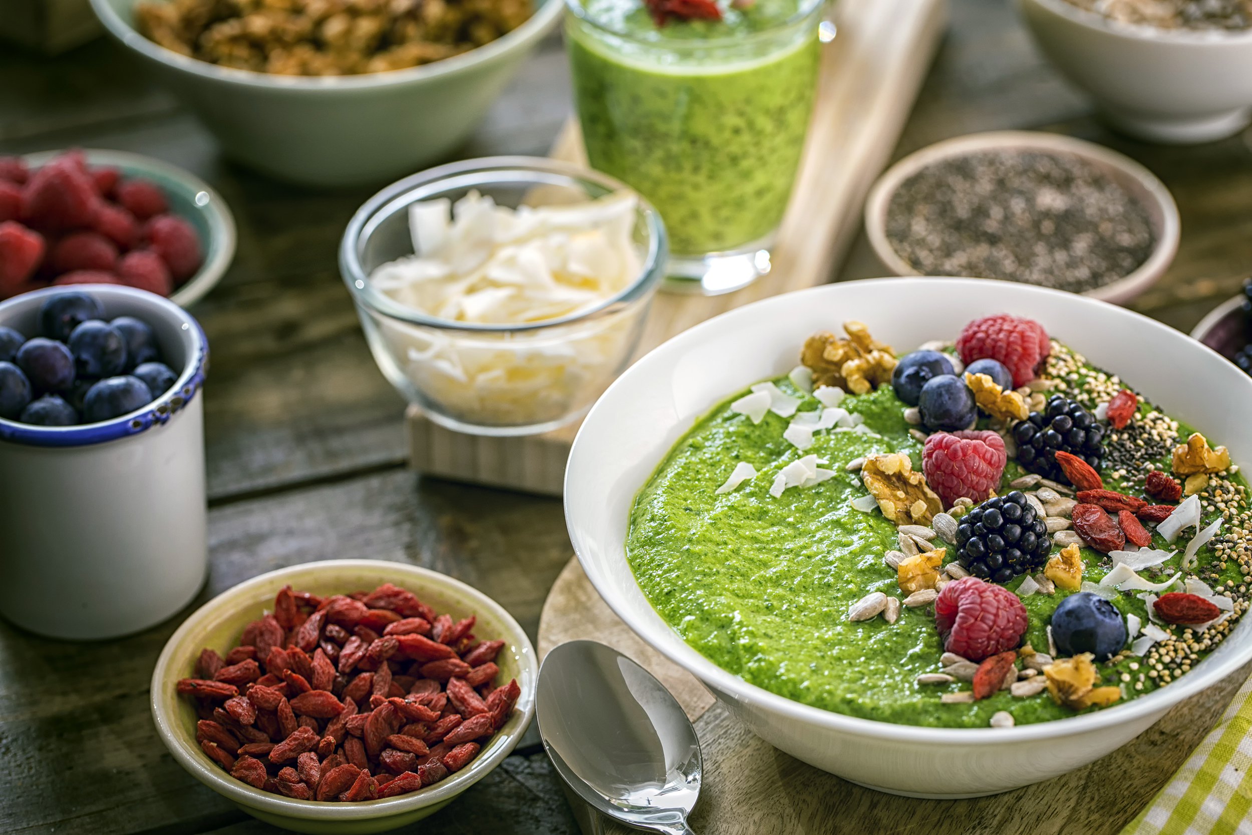 green breakfast smoothie in bowl with superfoods on top
