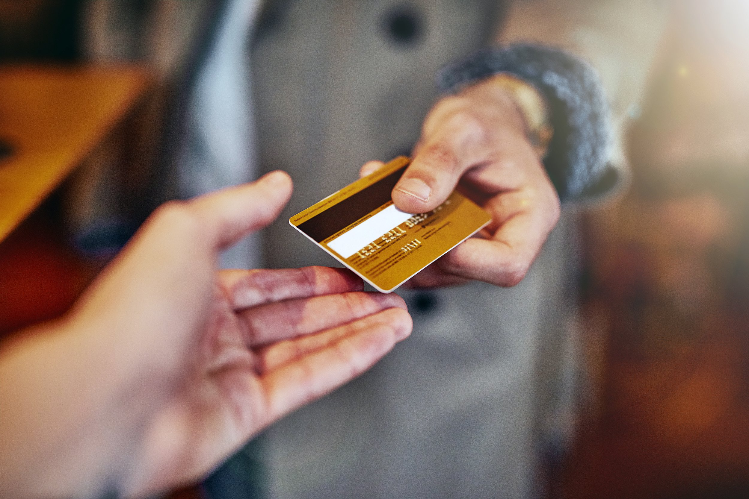 hand holding credit card giving to another hand