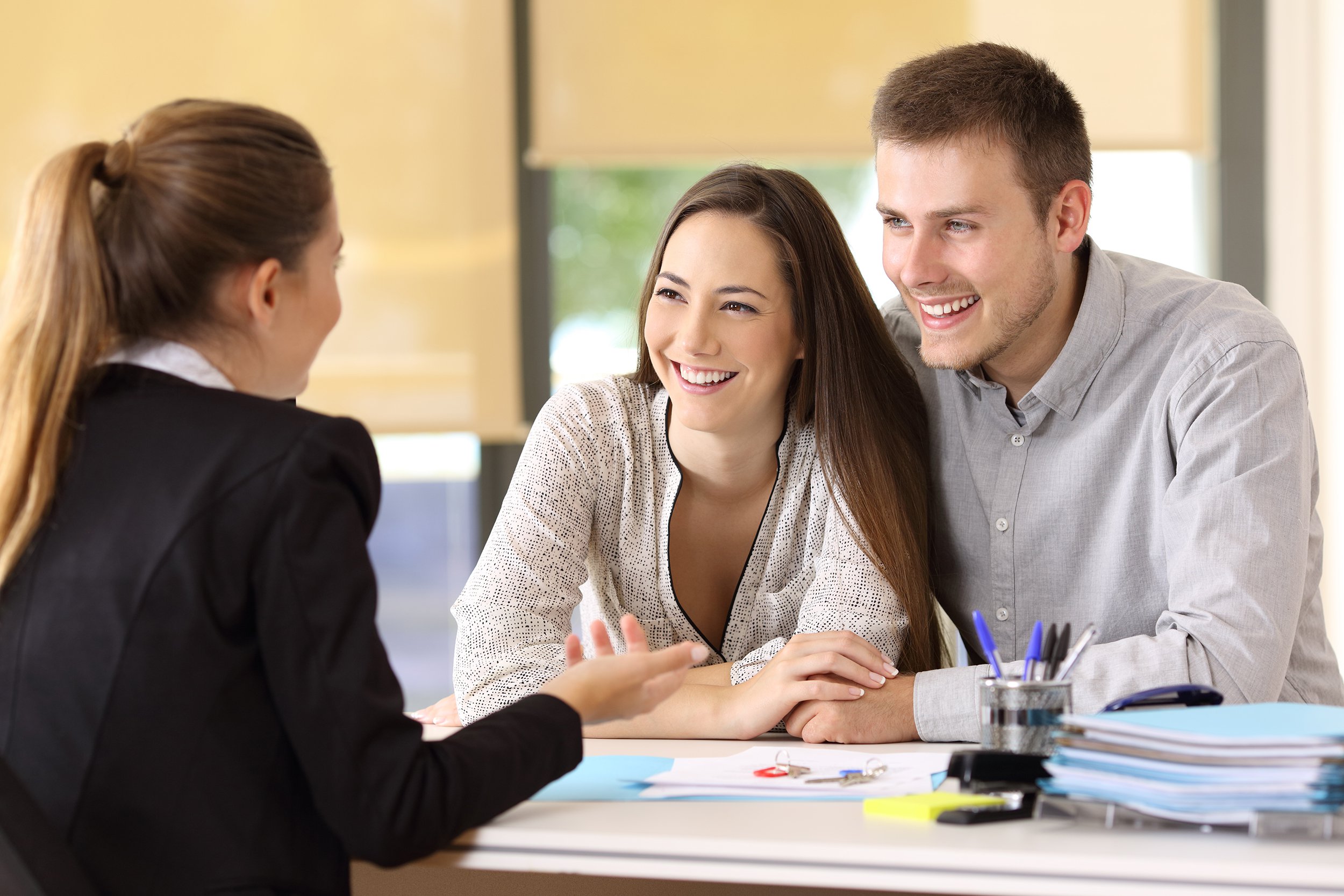 finance bank worker showing couple a calculator while they sit at a desk