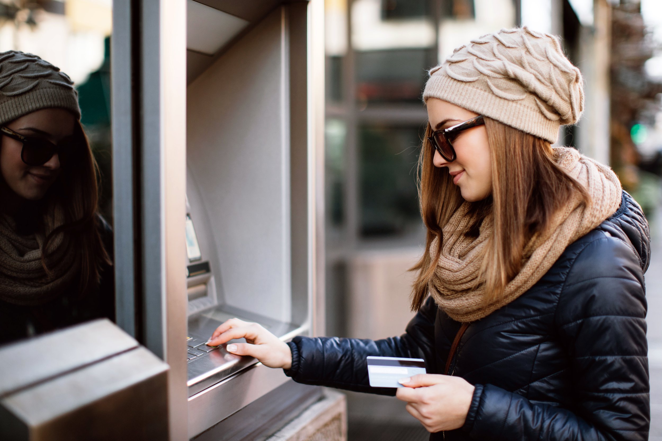 woman smiling while taking money at ATM