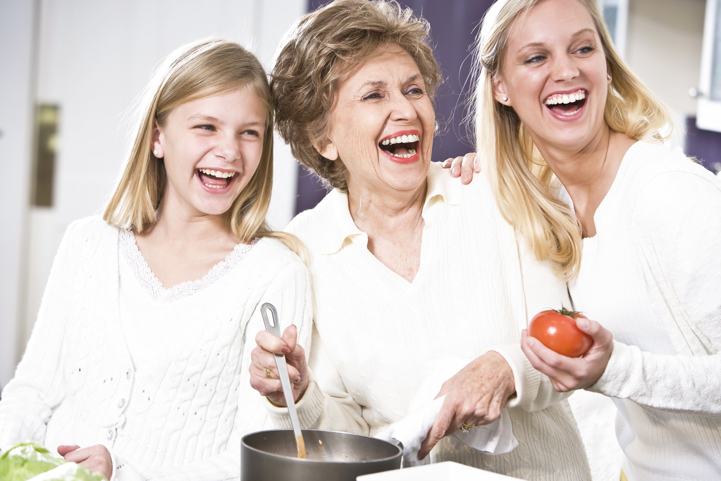 grandmother with family cooking in kitchen, smiling and laughing together