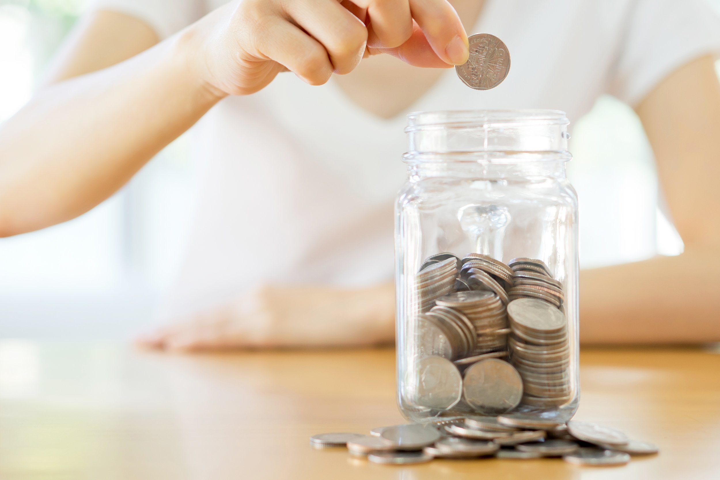 woman hands with coins in glass jar