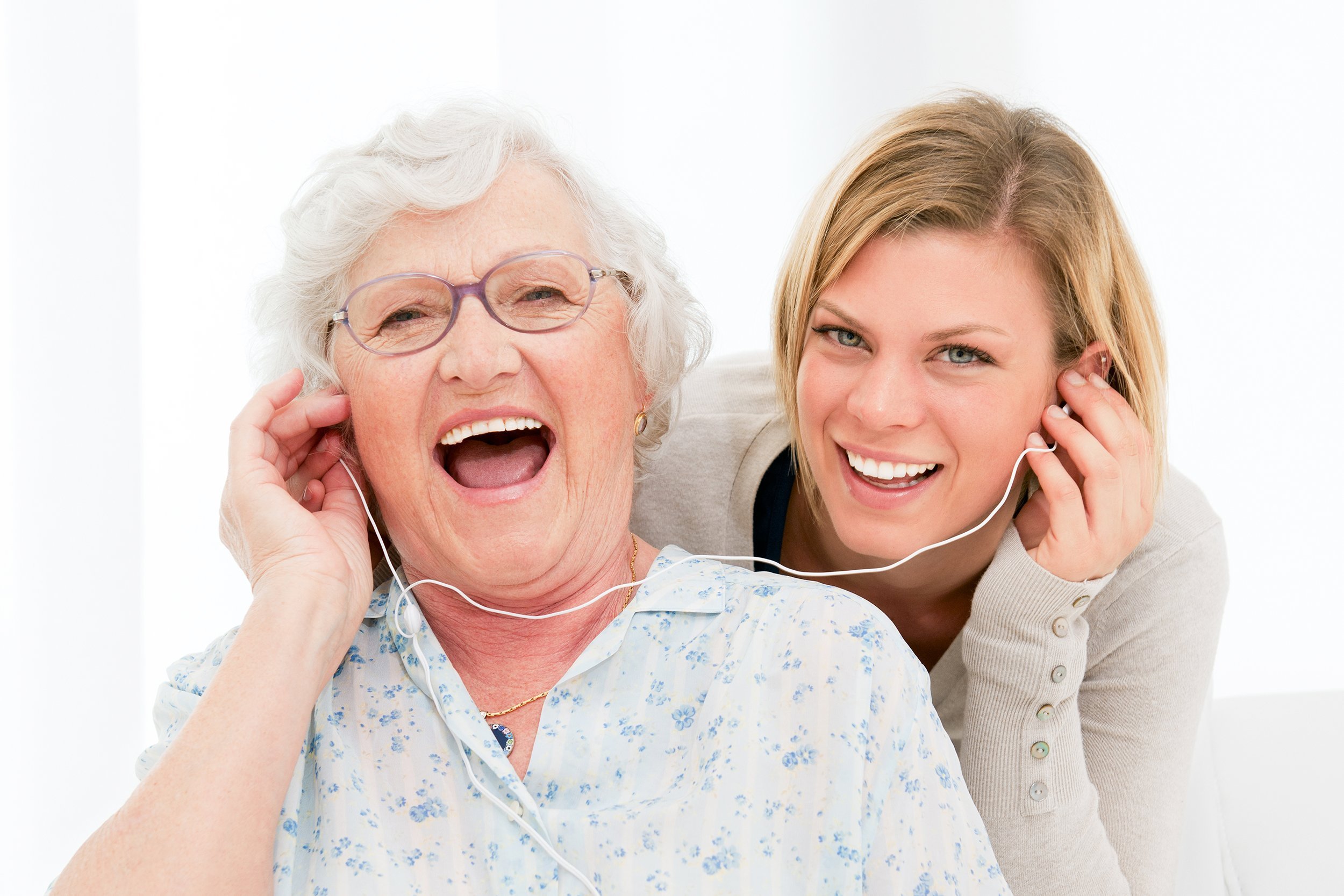 happy and excited grandmother listening music with her granddaughter at home
