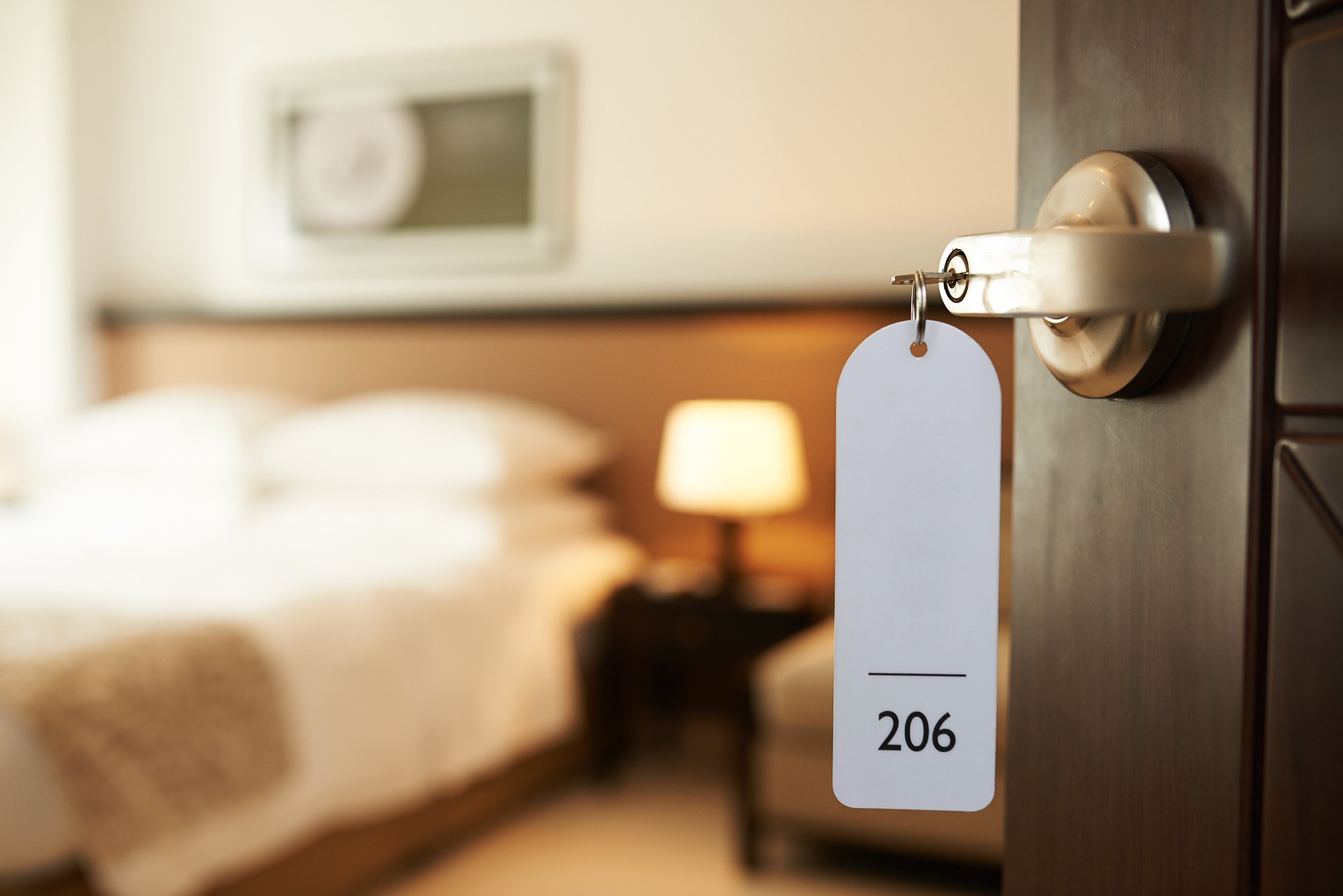 opened door of hotel room with key in the lock