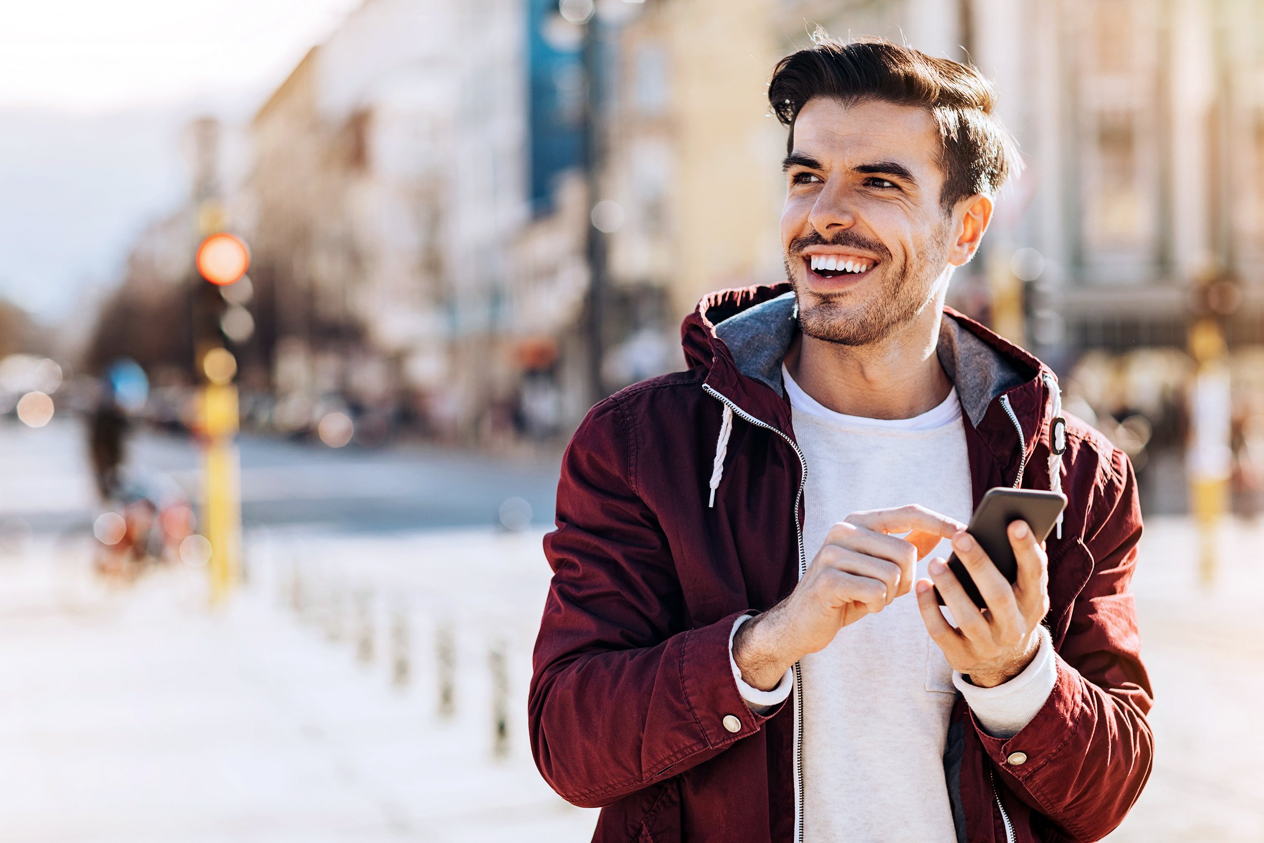 Happy man using smartphone walking outside