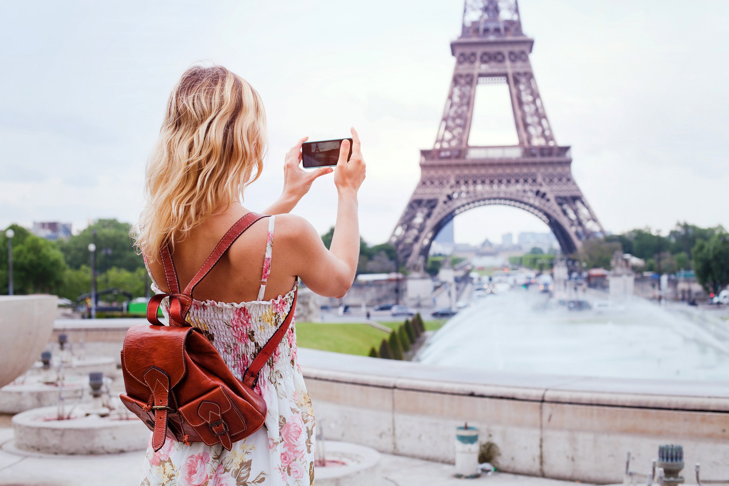 Young woman taking smart phone photo of the Eiffel tower