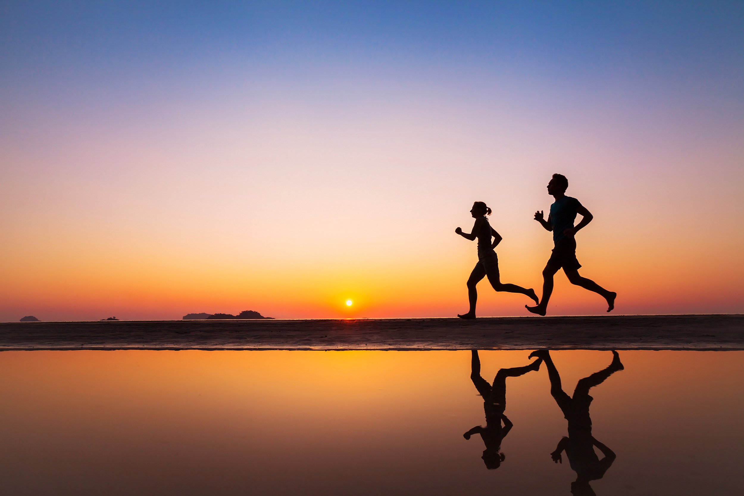 Silhouettes of two runners on the beach