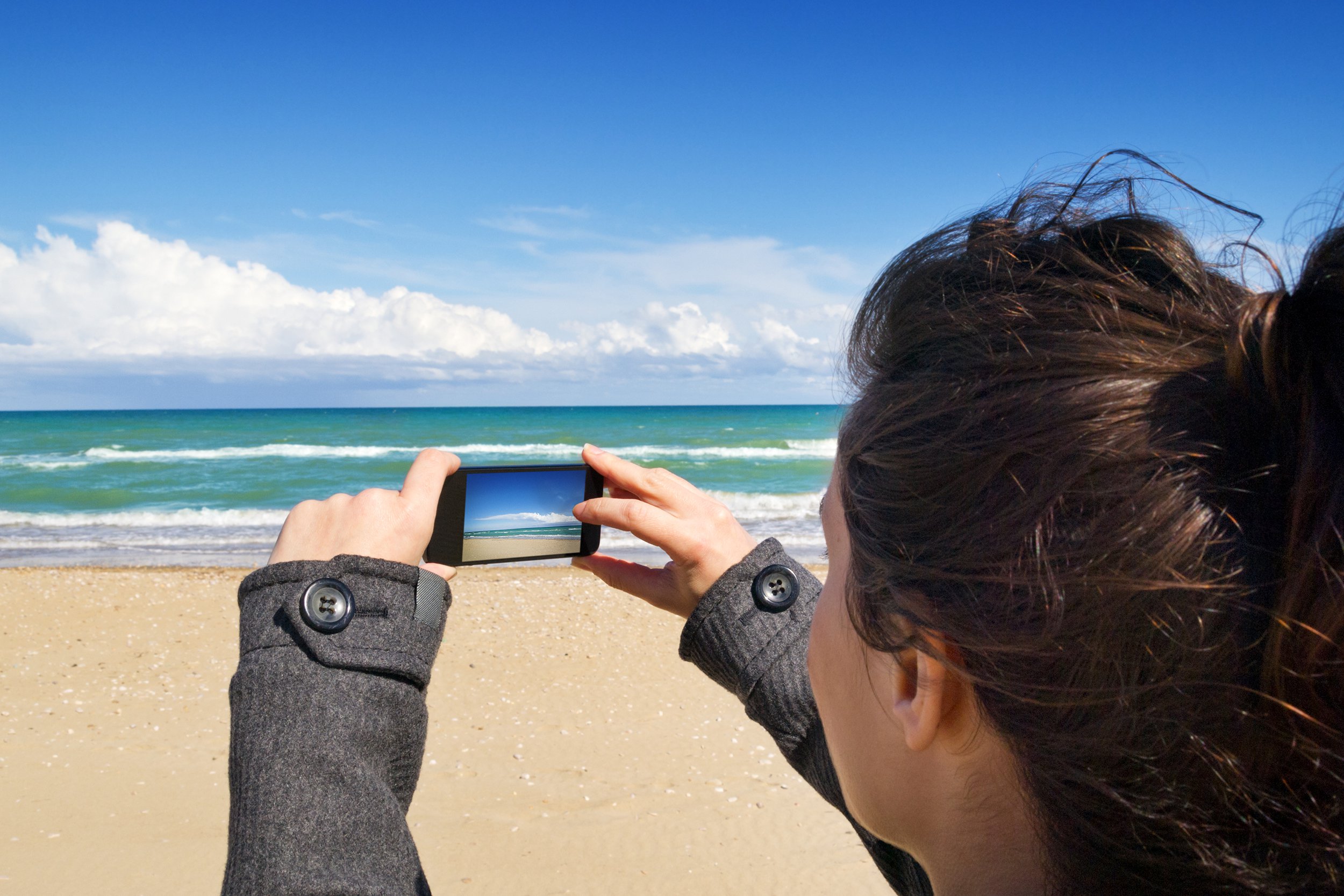 Woman taking photo of the beach shore