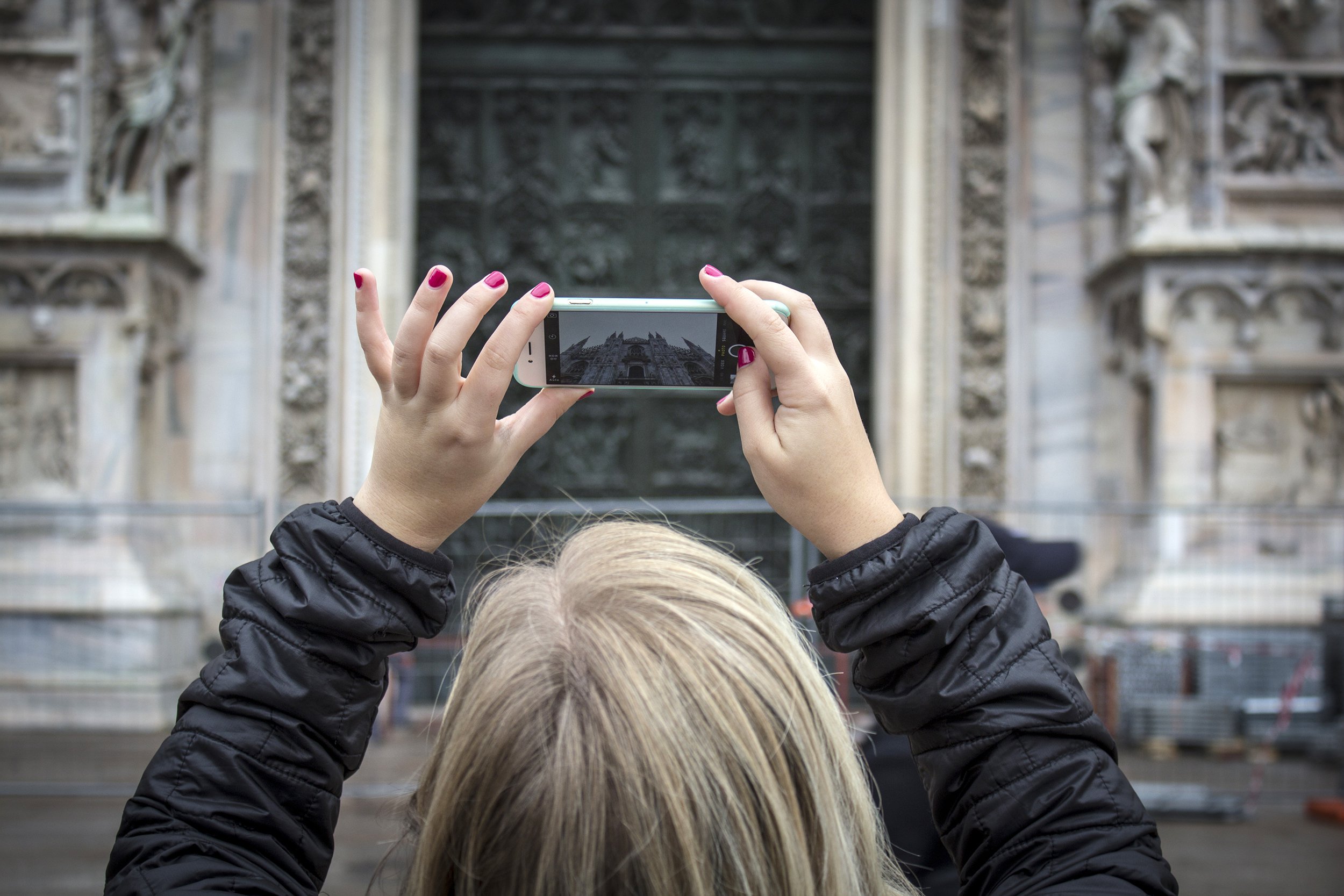 Woman taking picture of historical building on a cloudy day
