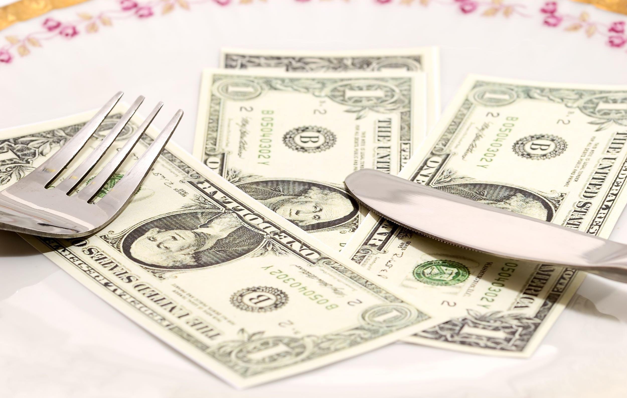 dollars in dish with a fork and knife