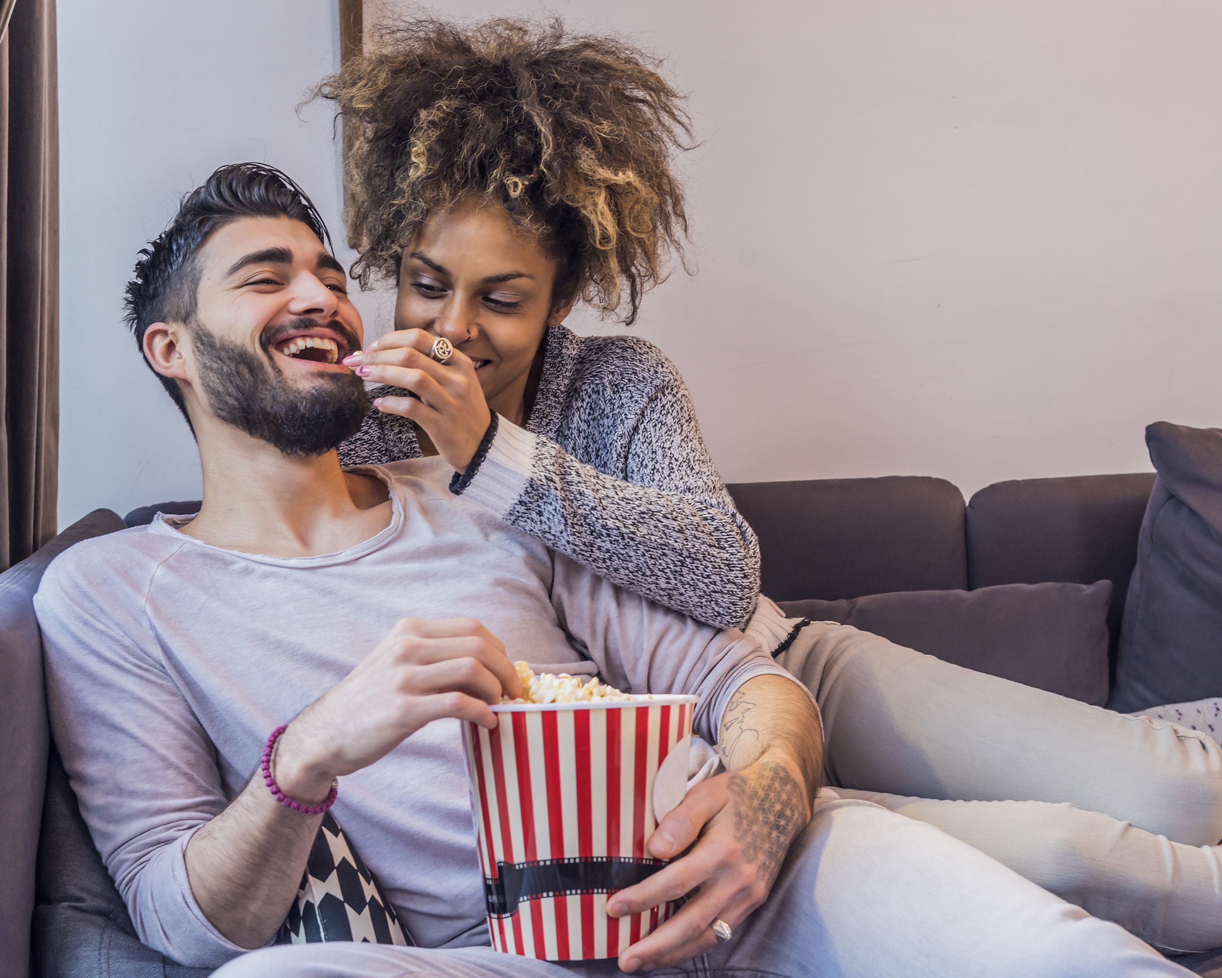 Happy couple on couch eating popcorn