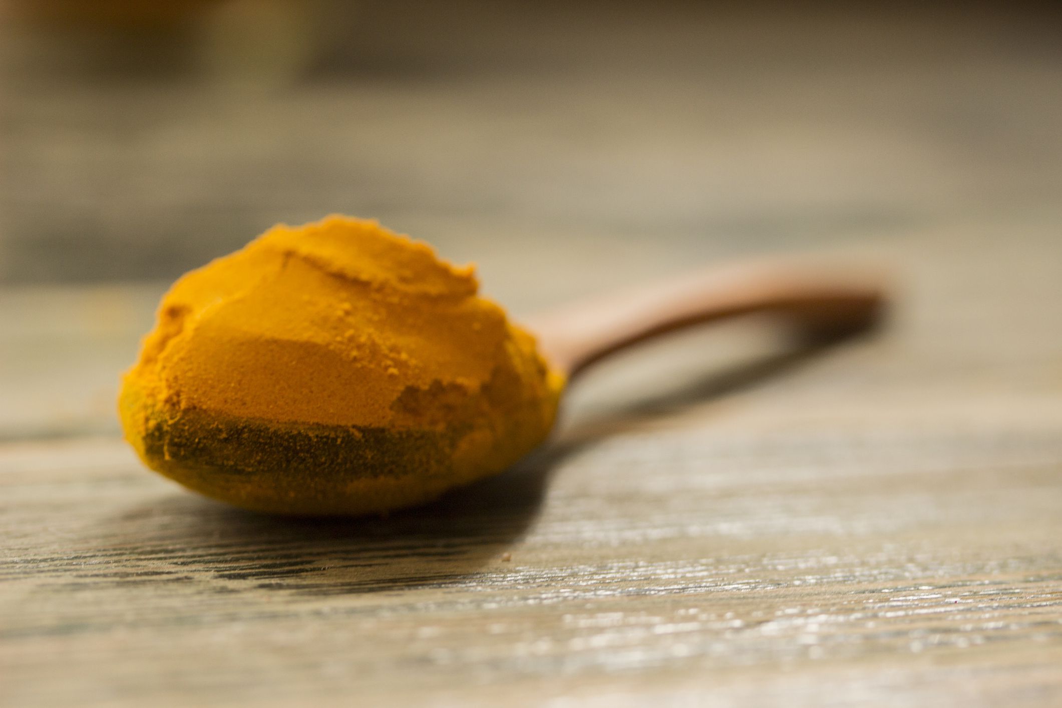 turmeric powder in a wooden spoon