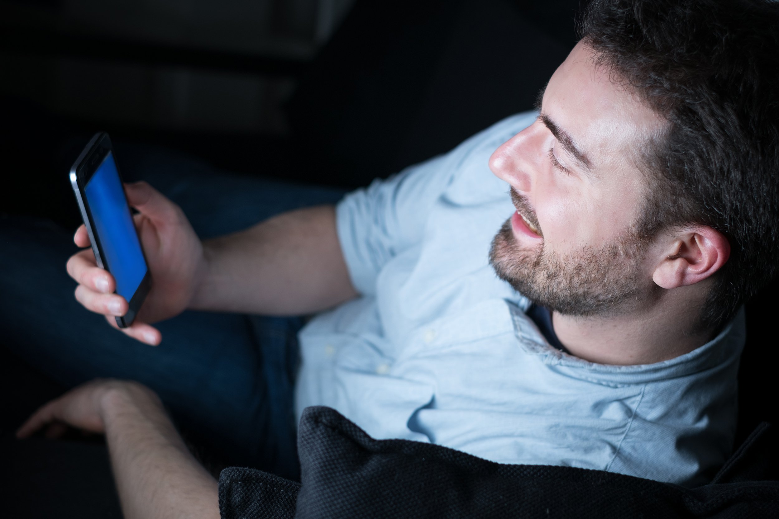 man looking at his mobile phone while sitting on couch