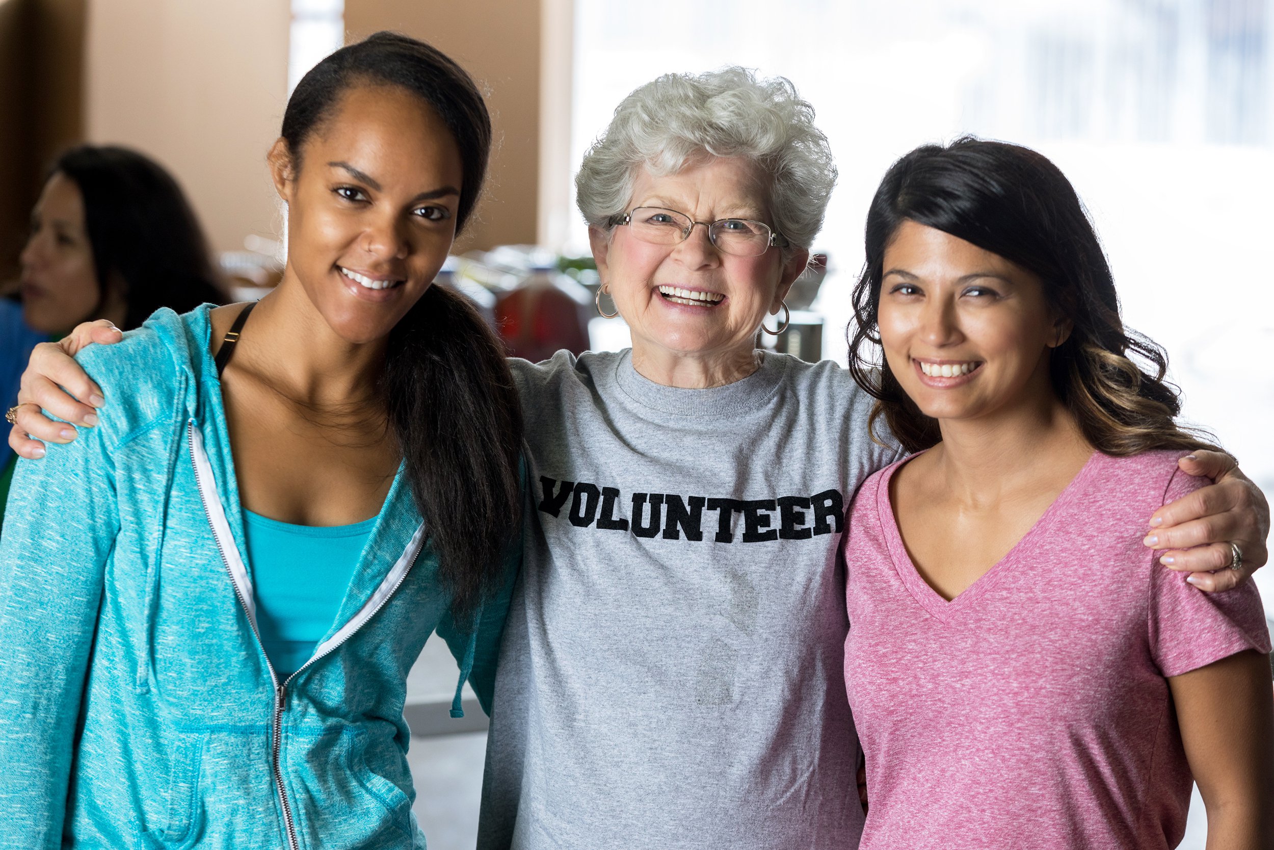 Senior woman volunteer standing next to two young girls