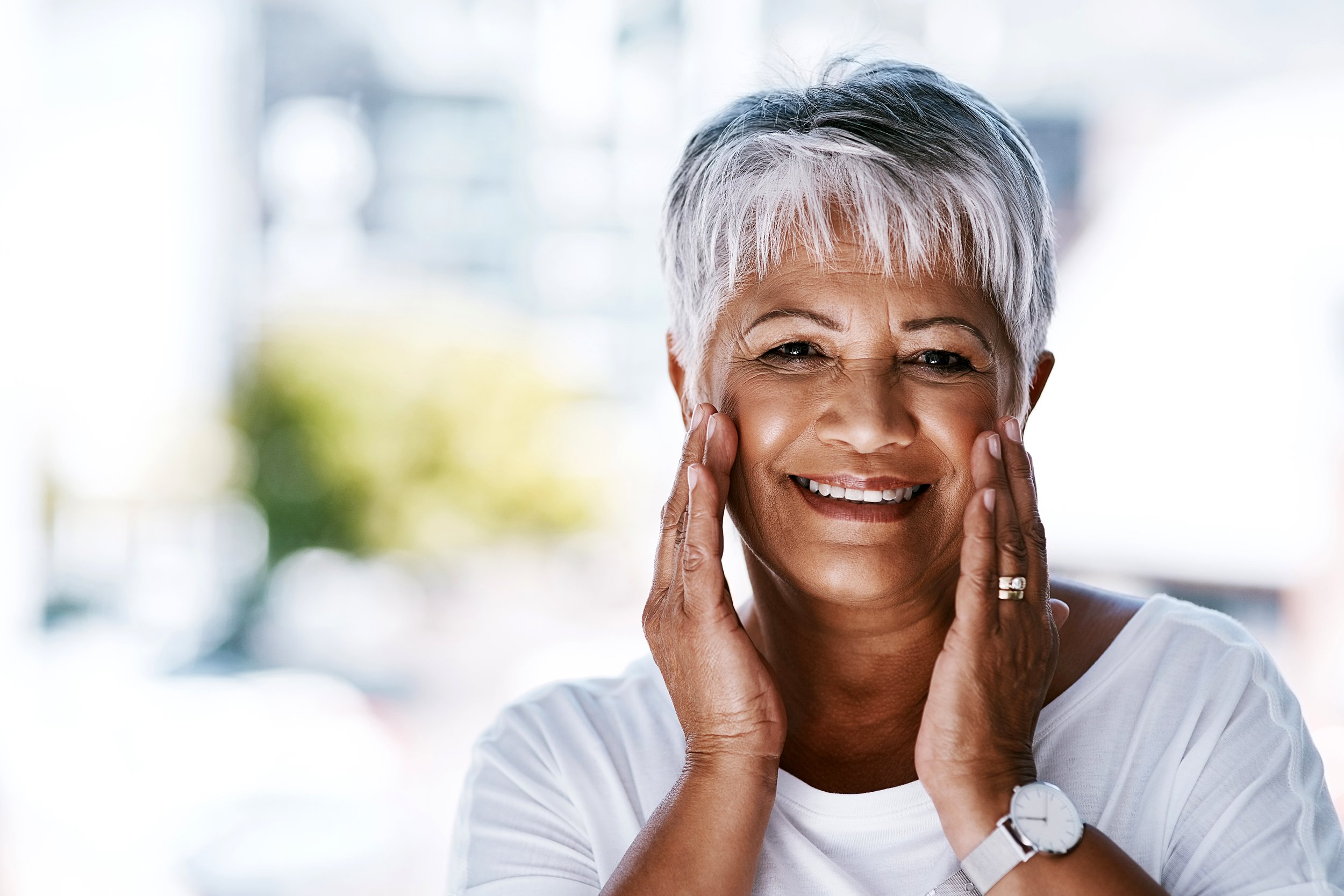 Smiling senior woman holding face