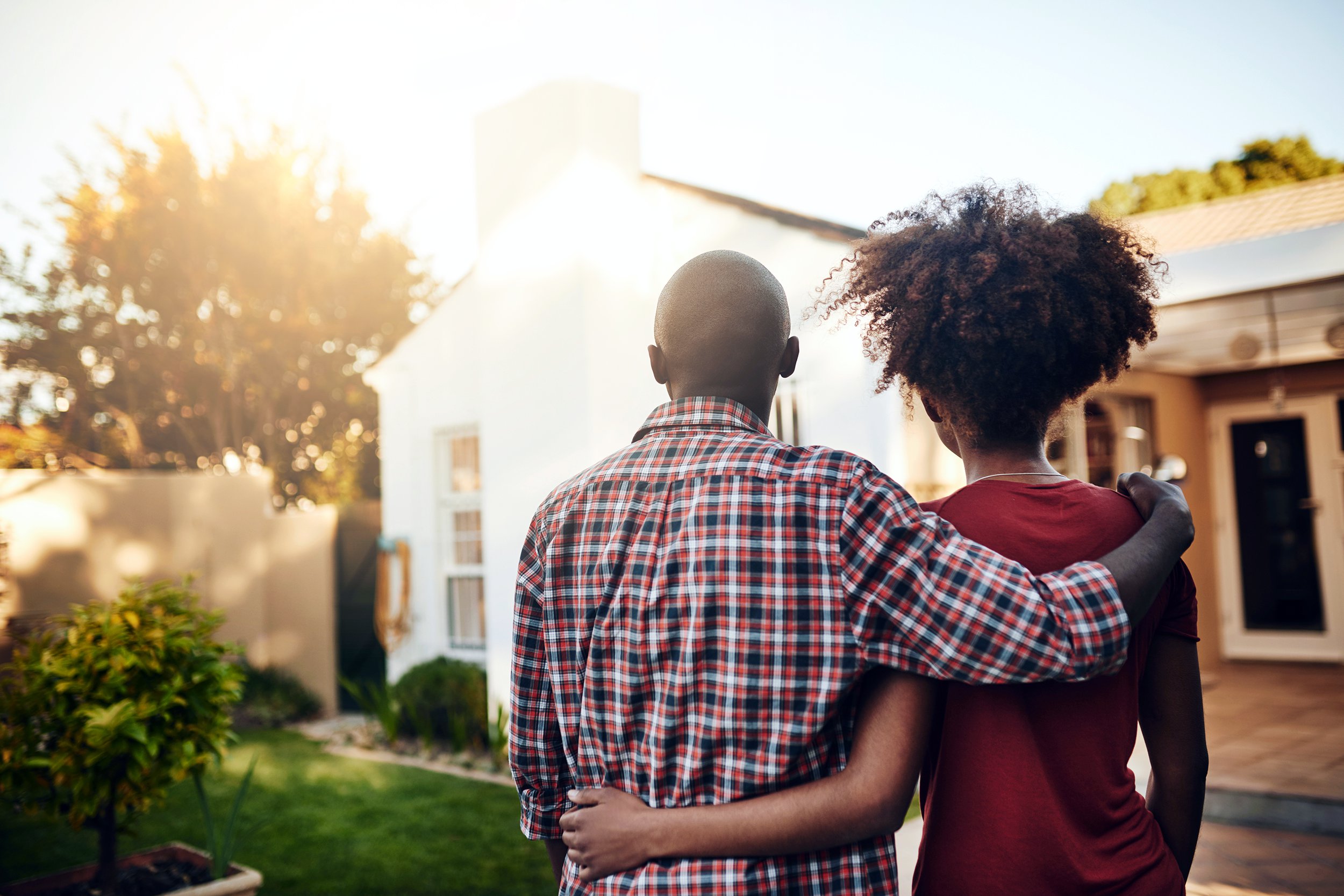 Couple standing outside of house as sun sets