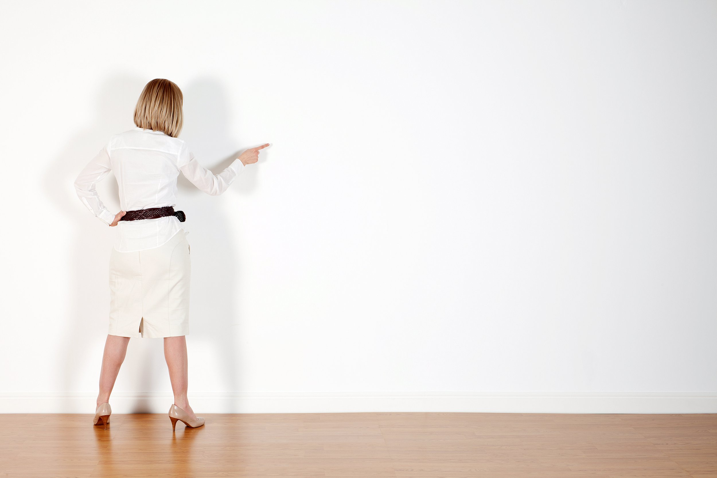 Woman pointing to spot on a blank wall