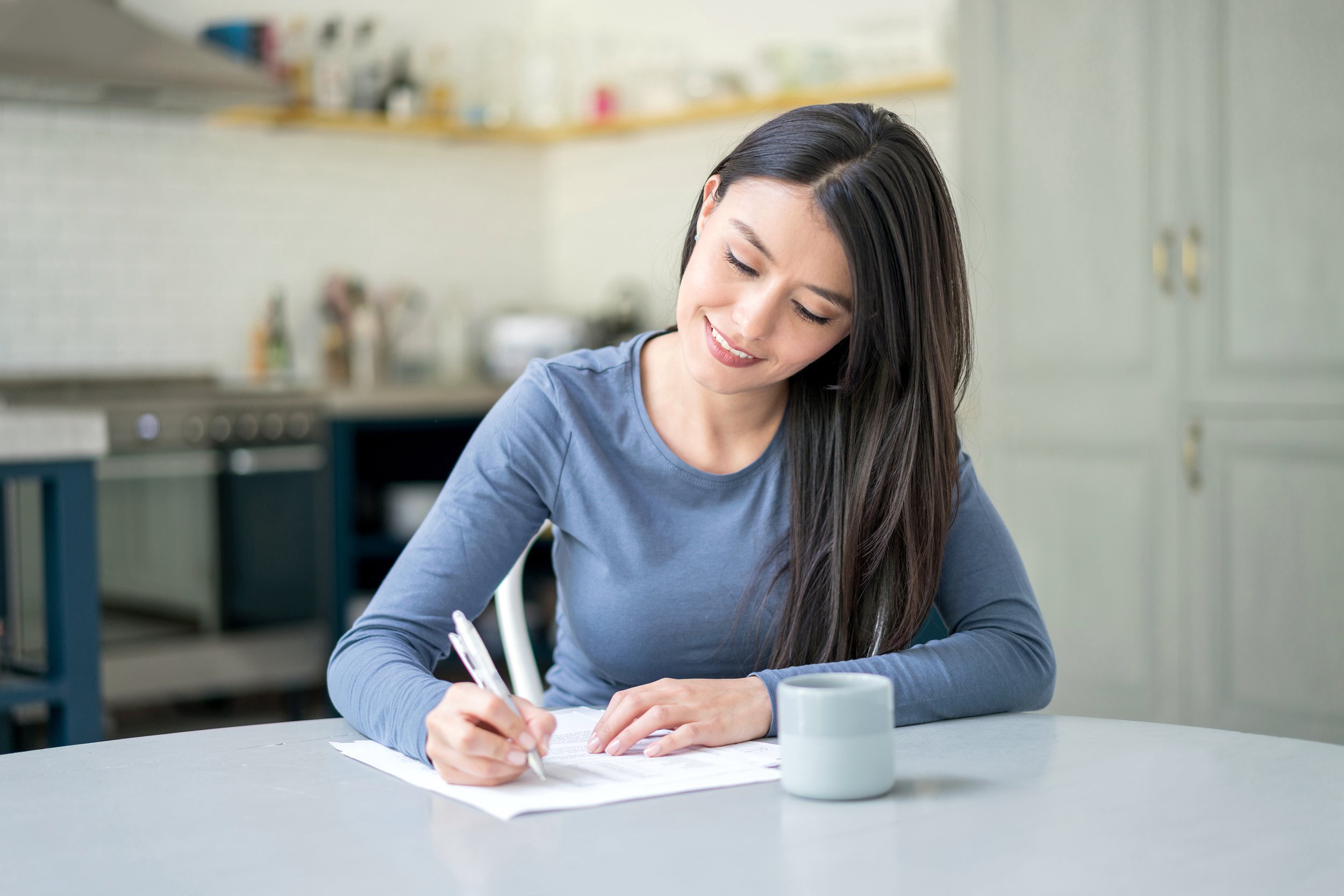 Woman writing a letter at kitchen table