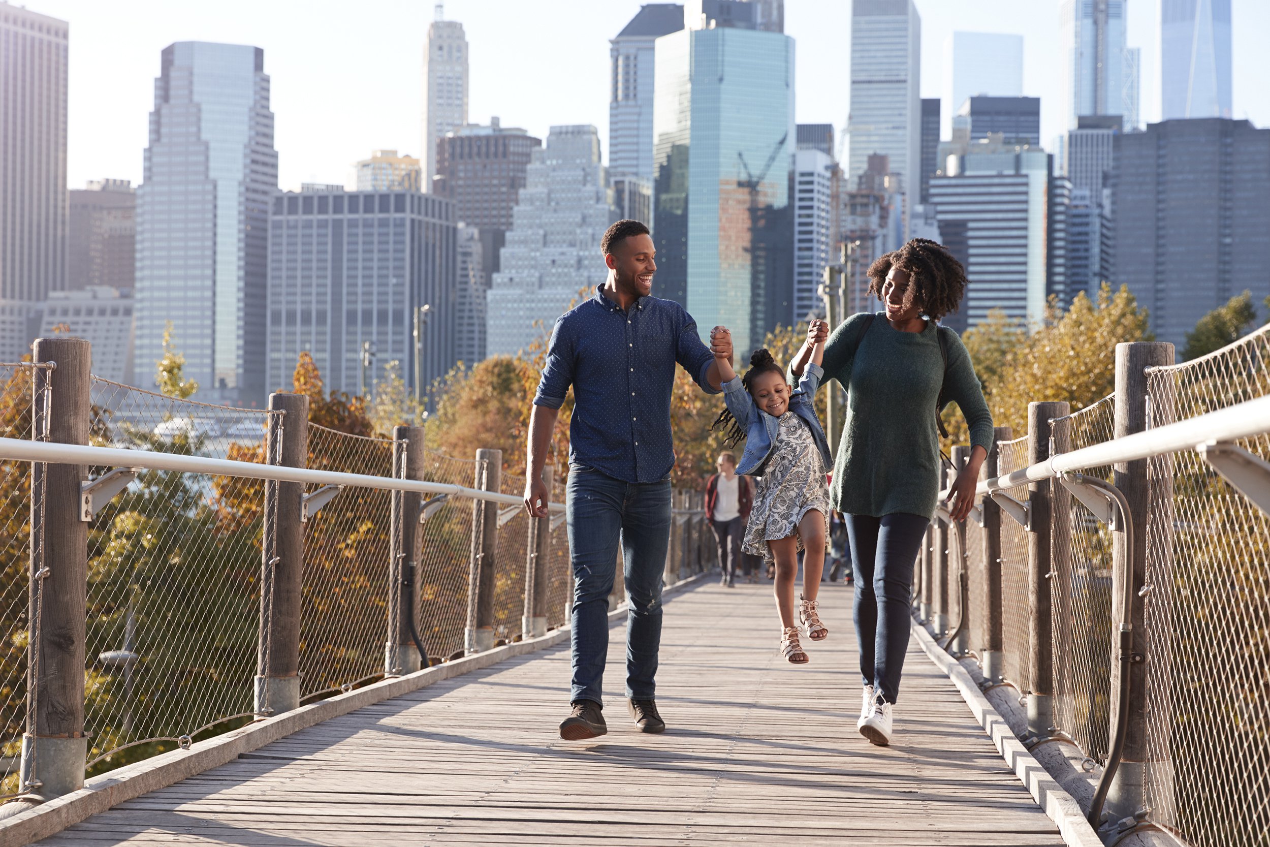 young family with daughter taking a walk on footbridge