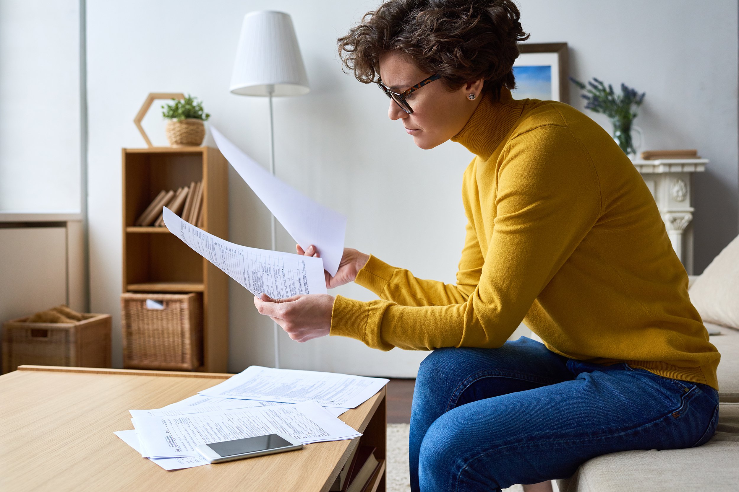concentrated woman reviewing financial documents at home