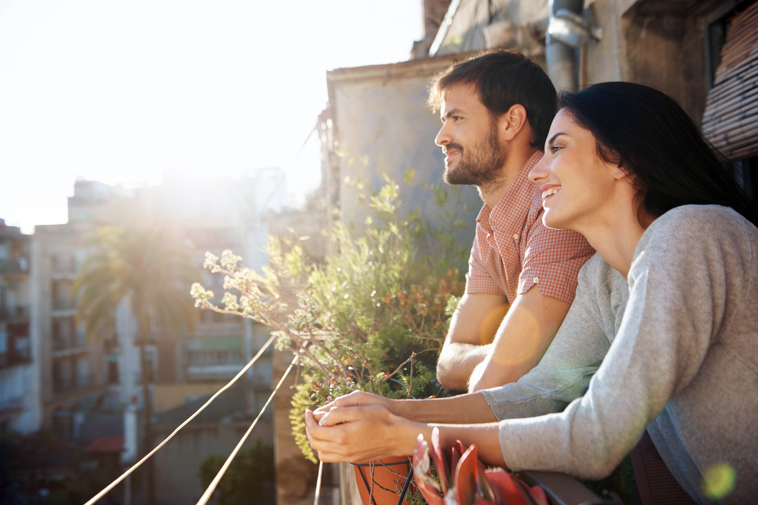 couple standing on balcony, looking over city