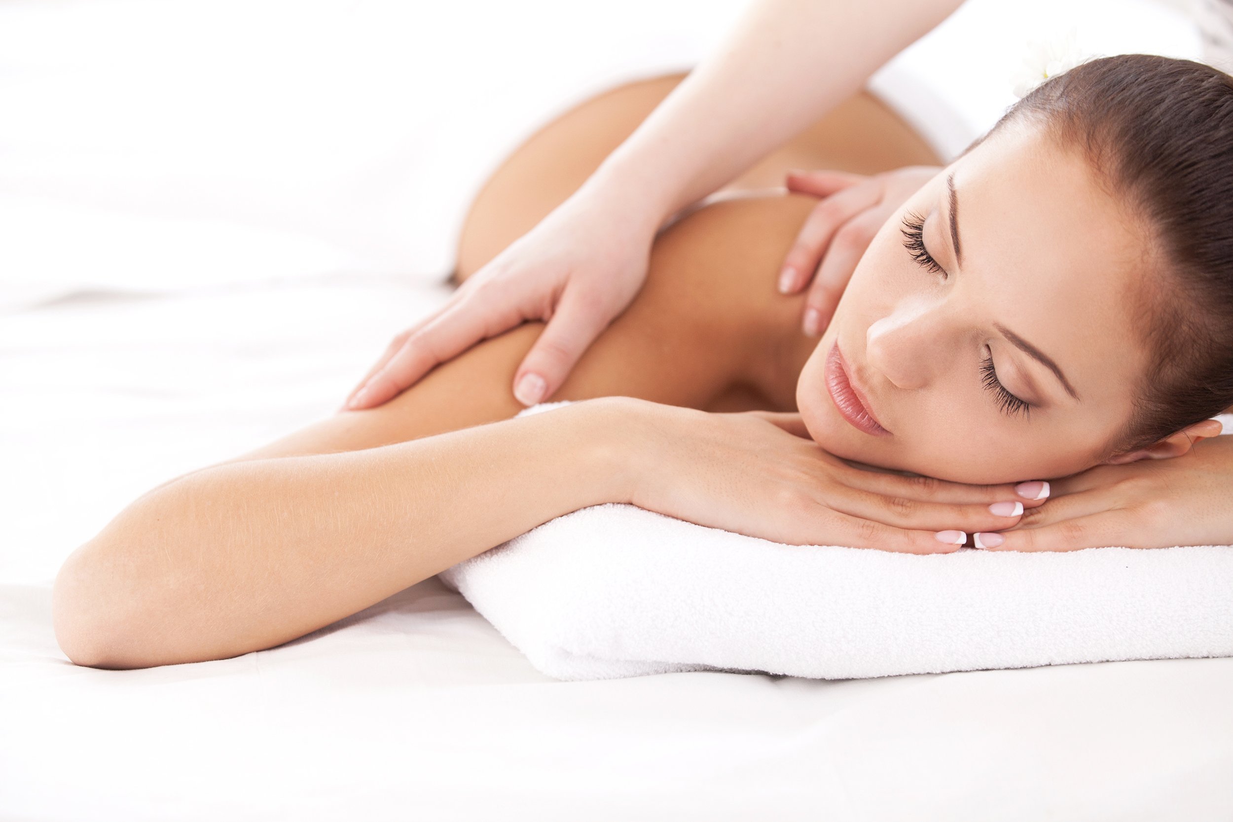 woman lying while massage therapist massaging her shoulders