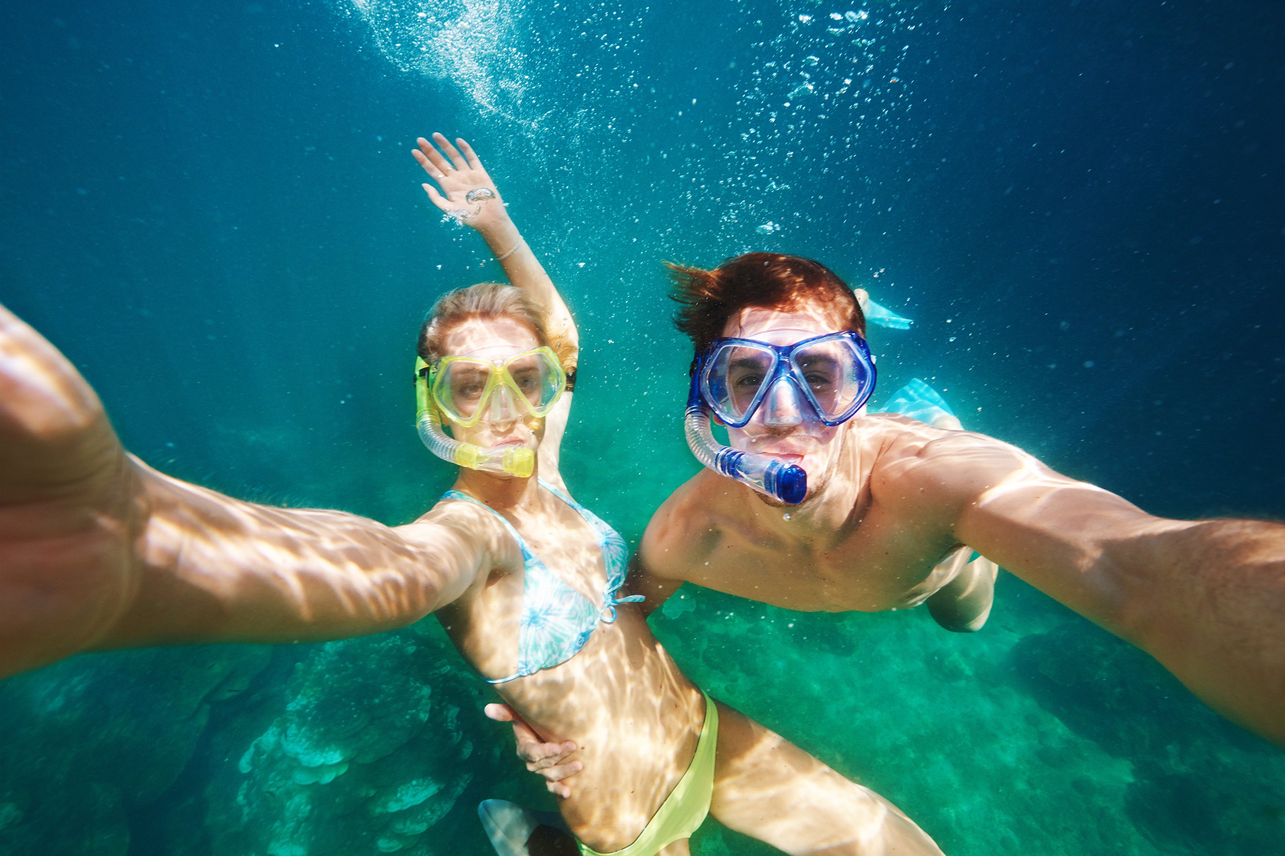 Couple scuba diving and smiling at camera