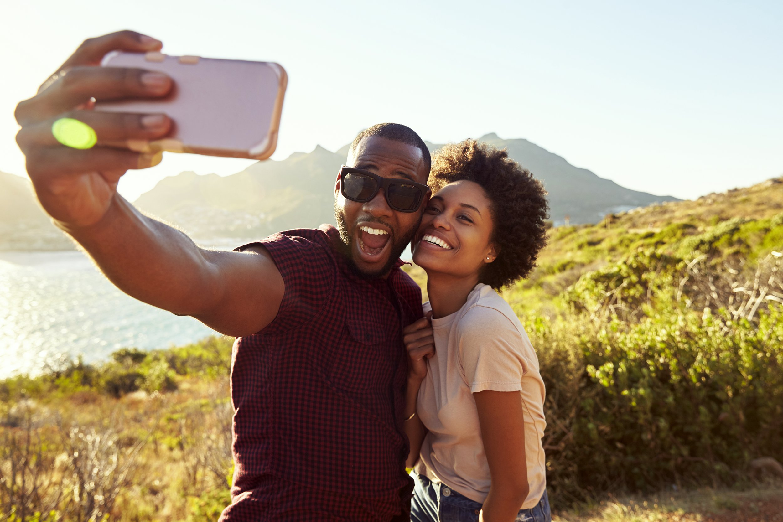 Happy couple taking a selfie on vacation near mountains