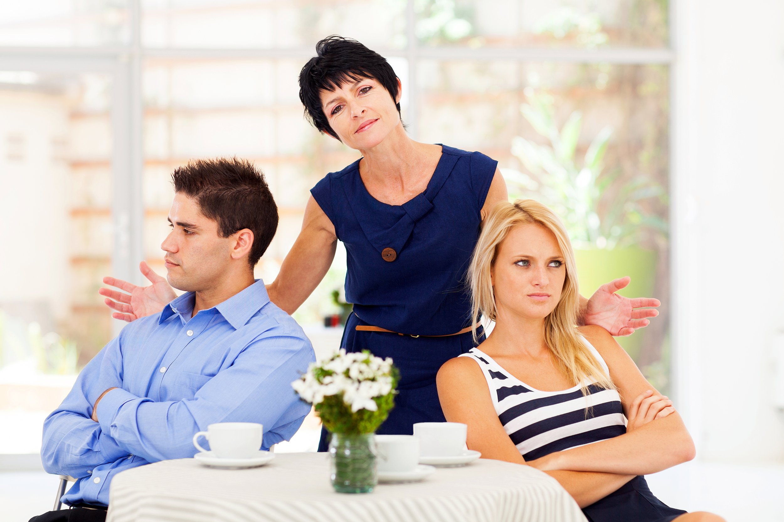 Mother-in-law standing between annoyed couple