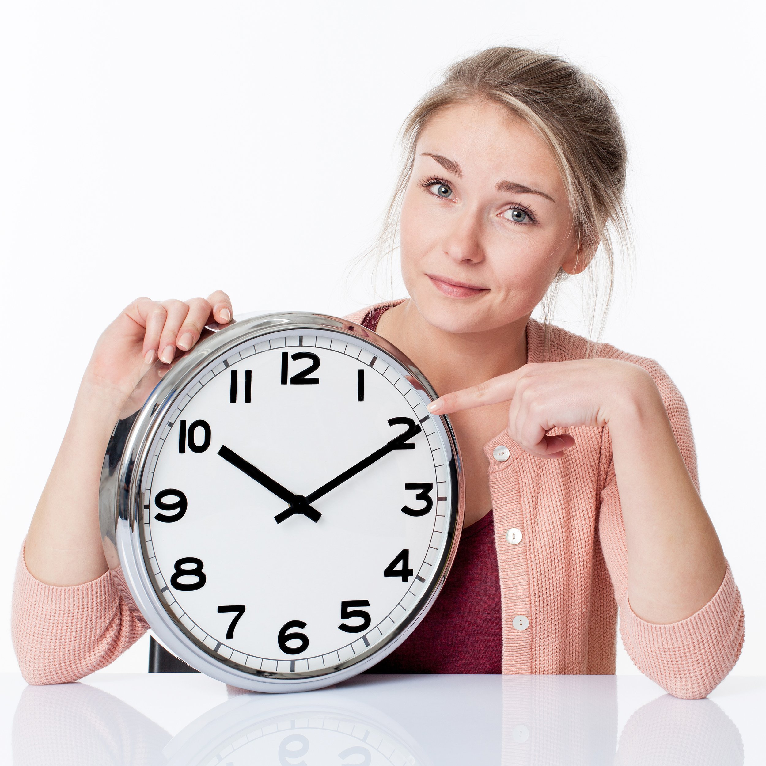 smiling young woman pointing to a clock