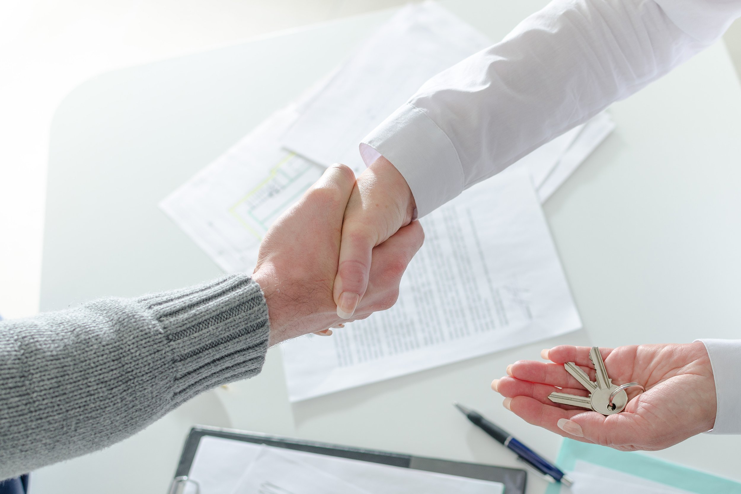realtor shaking hands with his client after handing over the keys