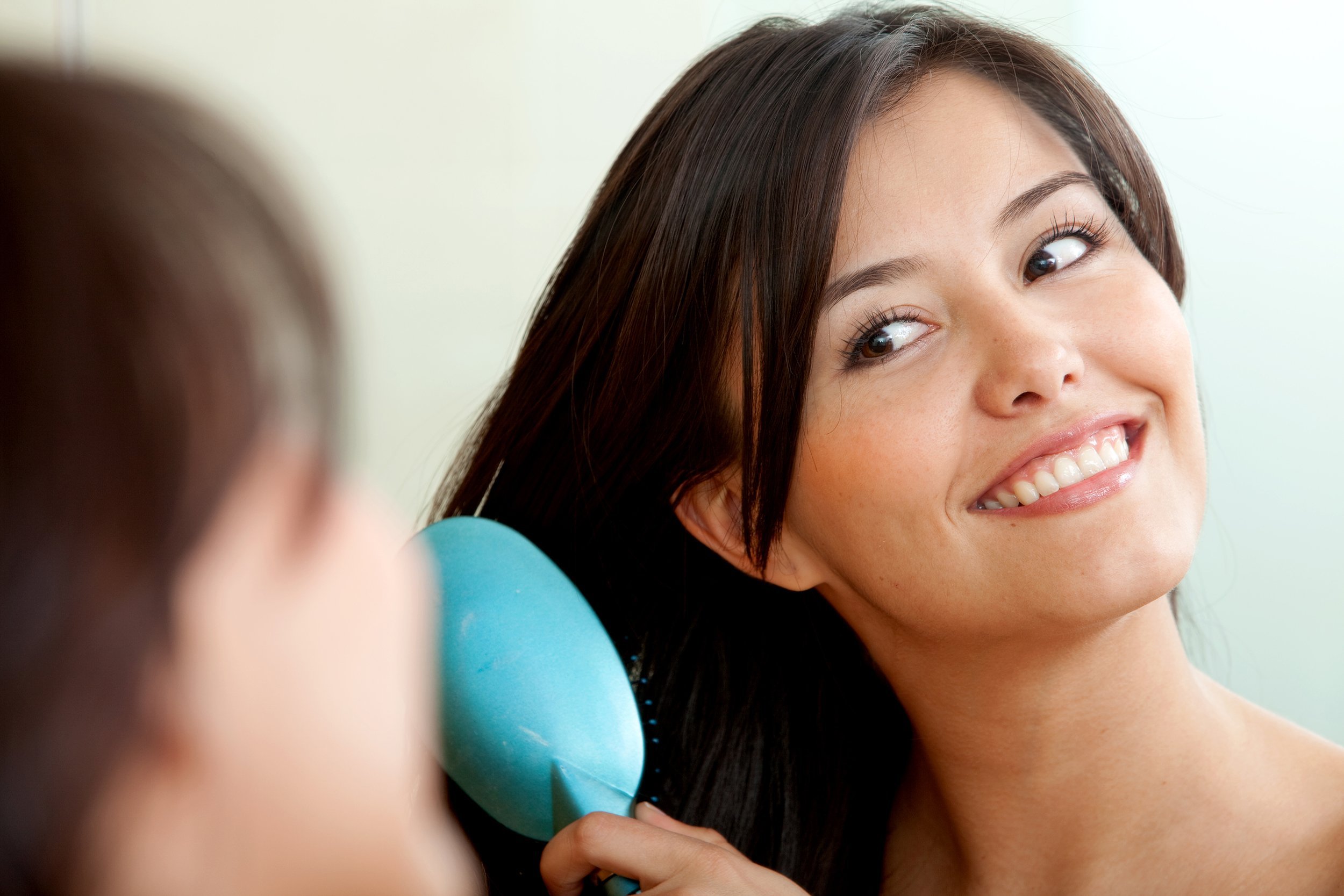 Woman in front of mirror brushing hair