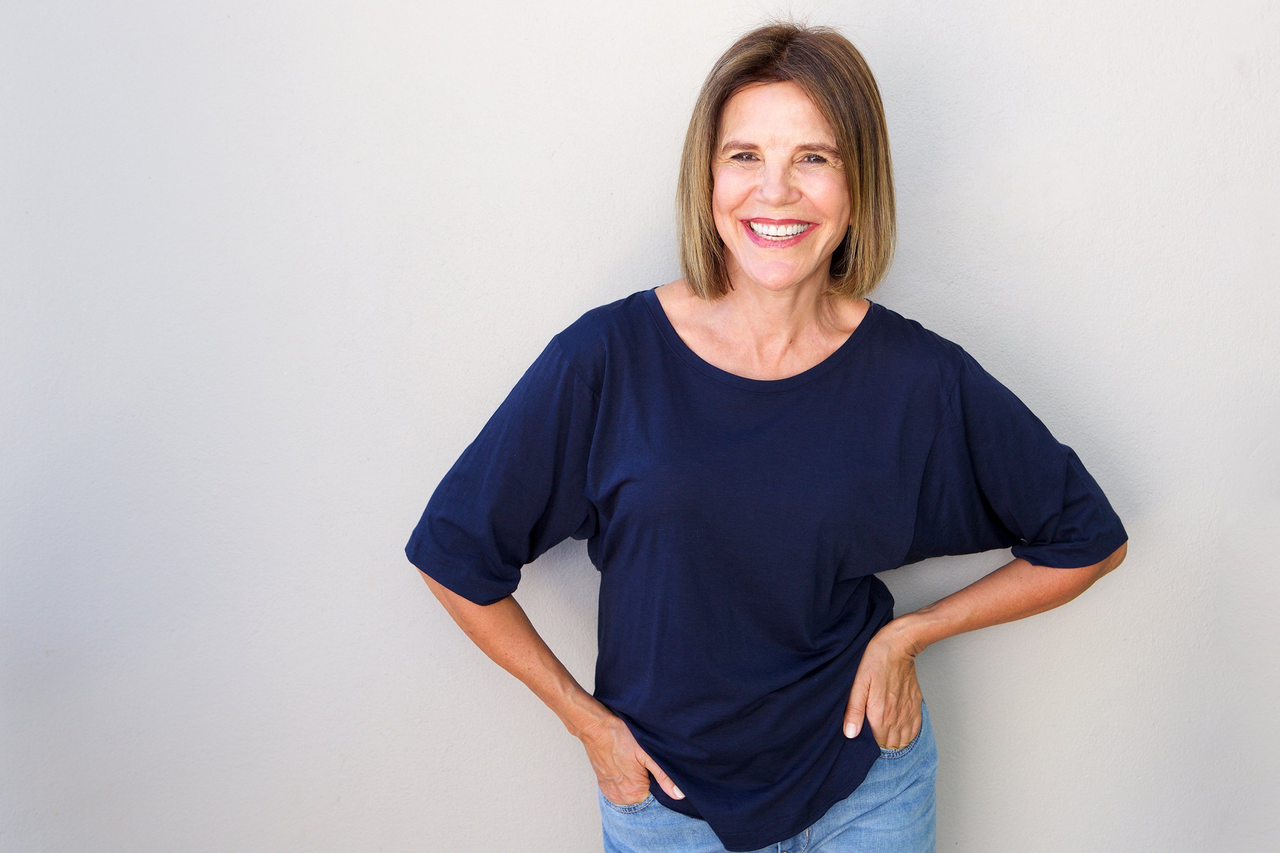 Middle-aged woman wearing simple clothes in front of a background