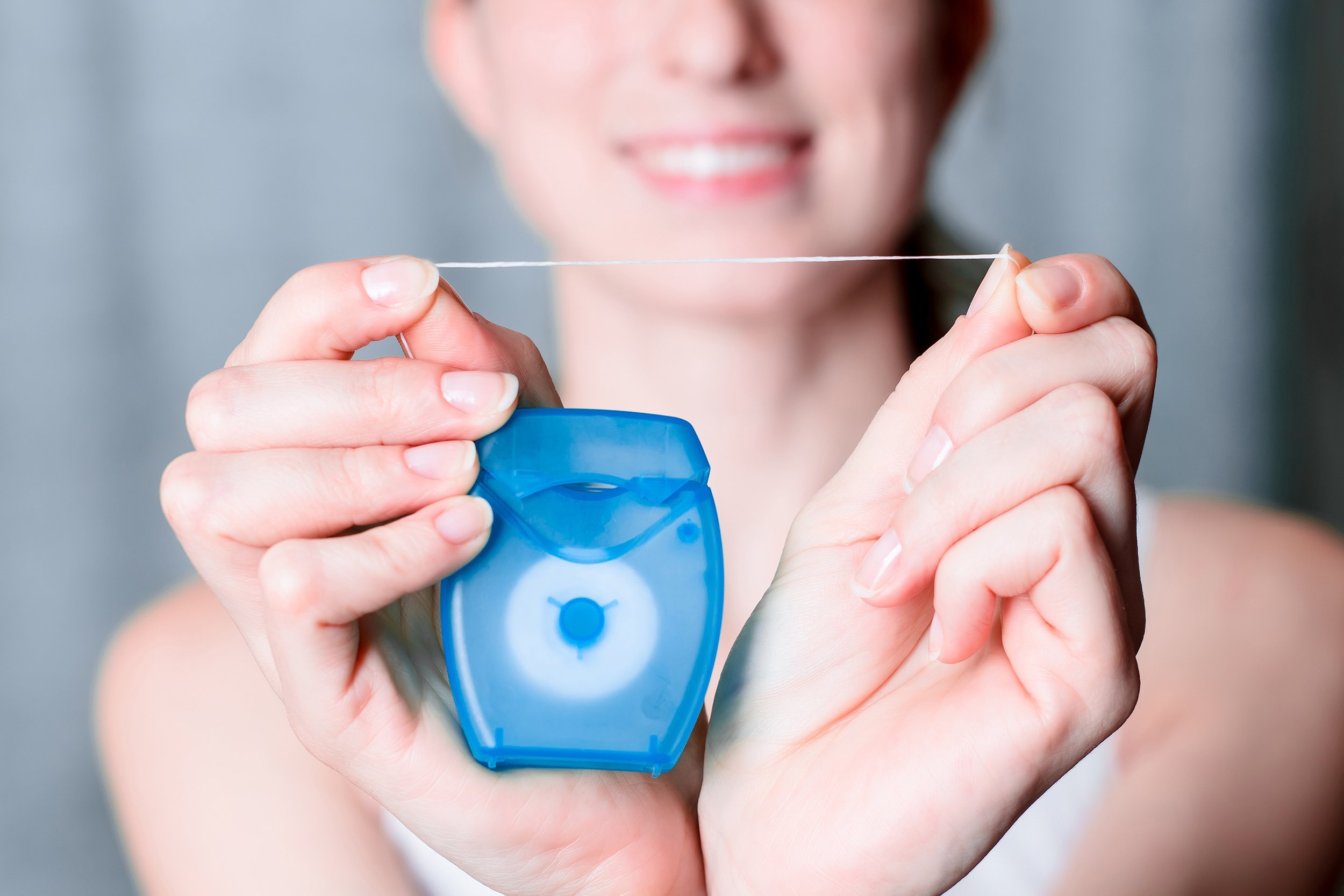 Closeup of dental floss with woman in the background